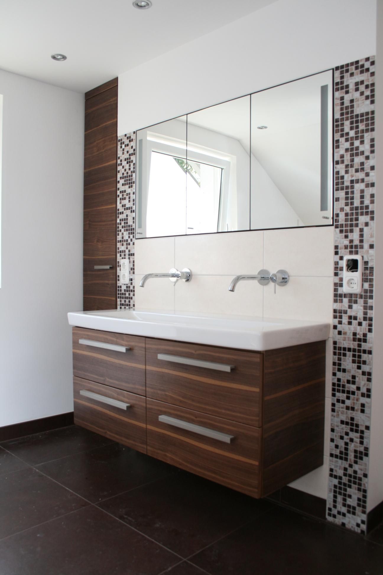 Moderner Waschtisch fürs Badezimmer mit Holzschränken, weißem Waschbecken, Wandspiegel und Mosaikfliesen-Akzenten