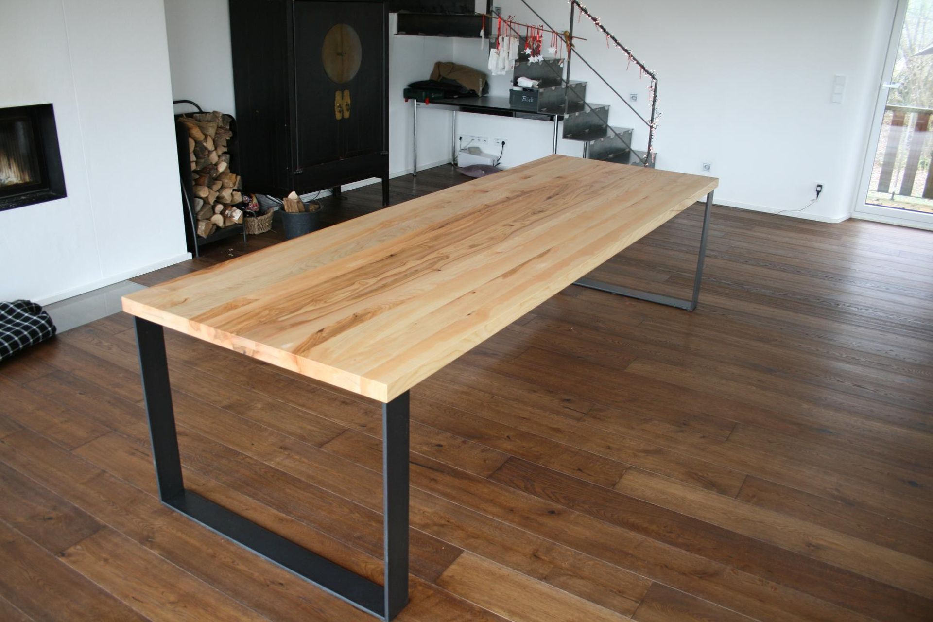 Langer Holztisch mit schwarzen Metallbeinen in einem modernen Raum mit Parkettboden