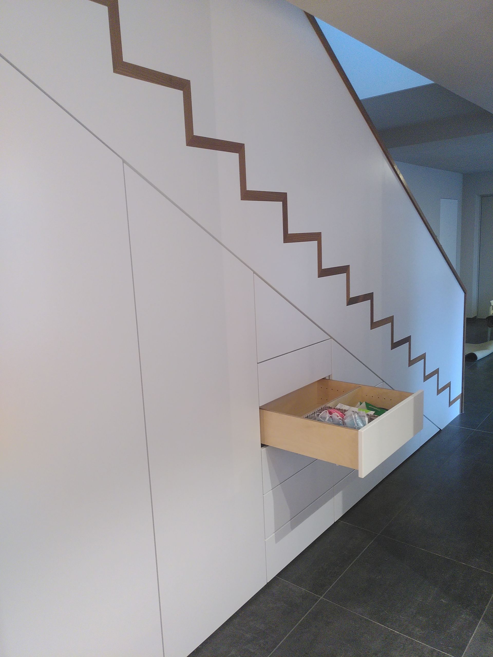 Wandgemälde einer Treppe mit einem kleinen Wandregal, auf dem bunte Gegenstände stehen