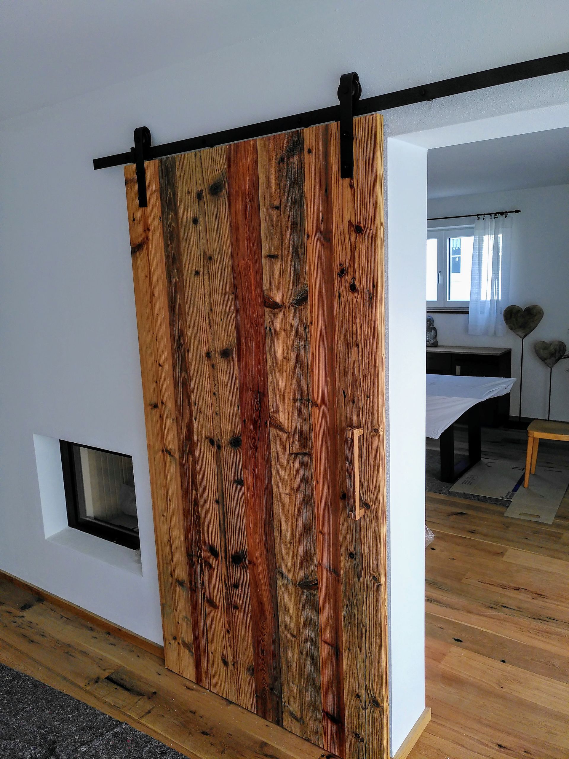 Rustikale Schiebetür im Scheunentor-Stil mit schwarzer Beschlagtechnik in einem hellen, modernen Wohninterieur