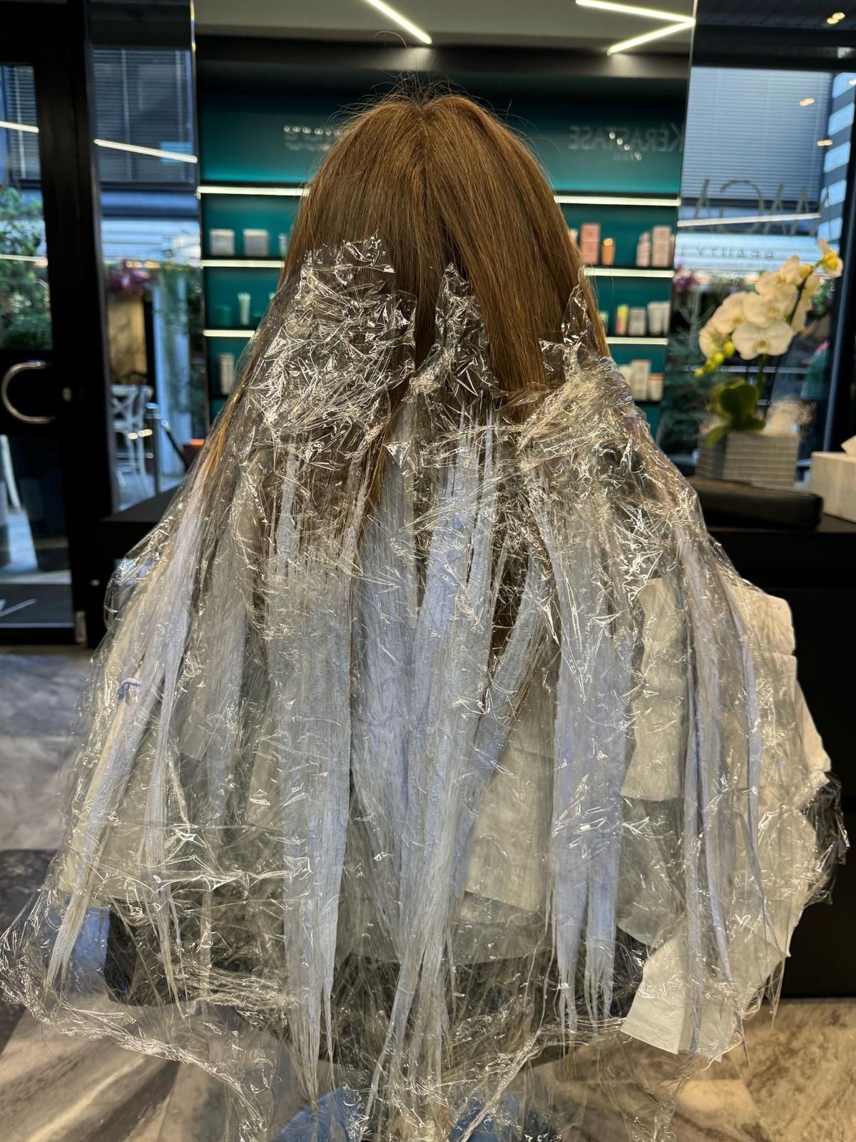 I capelli di una persona, divisi in sezioni e avvolti in diverse ciocche argentate, in un salone di parrucchieri professionale.