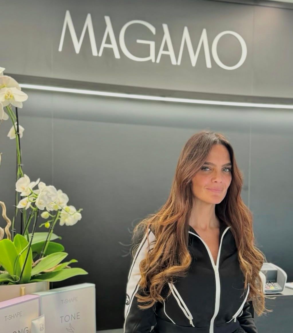 Una persona sorridente in piedi davanti a un cartello con la scritta 