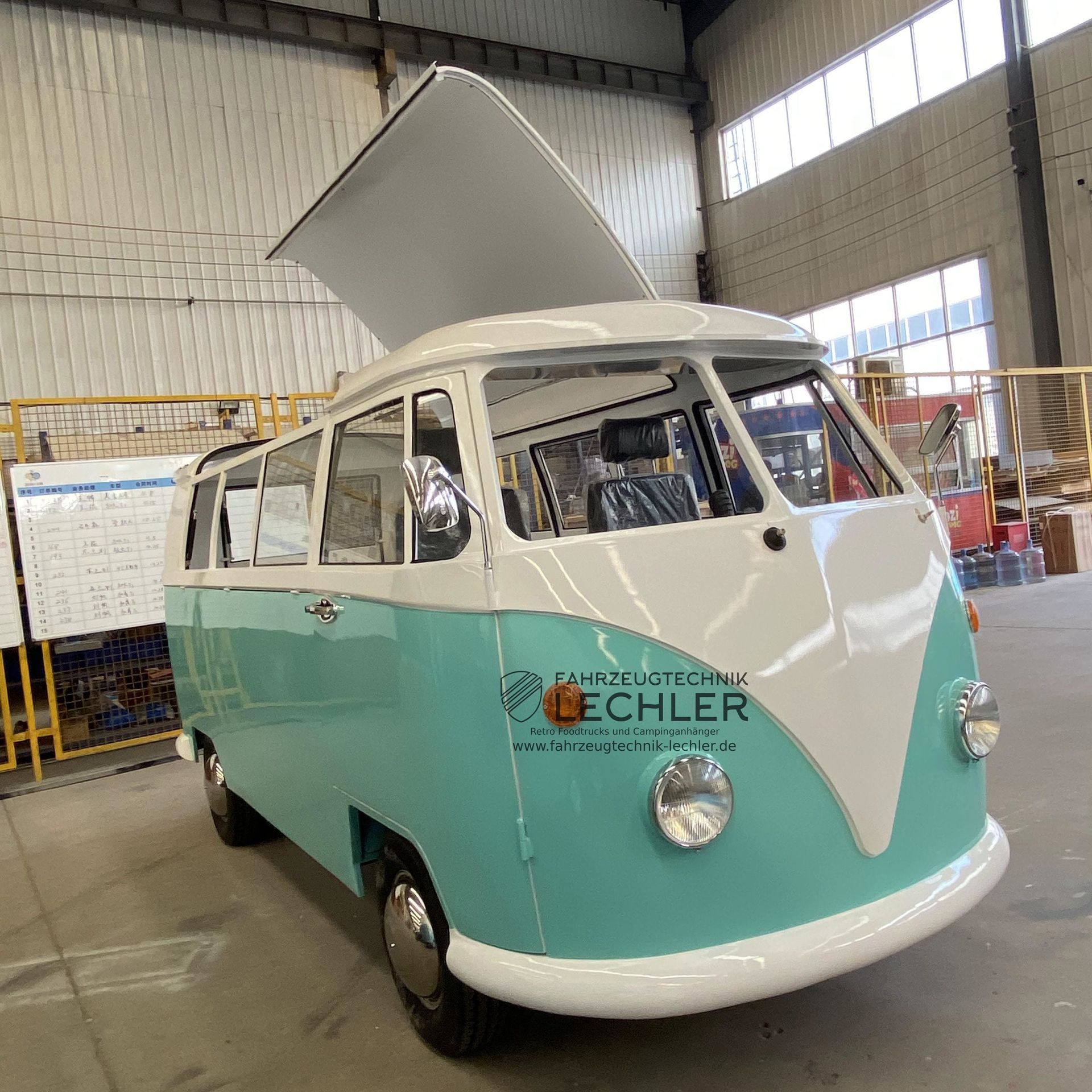Türkis-weißer VW-Bus mit geöffnetem Verdeck in einem Gebäude.