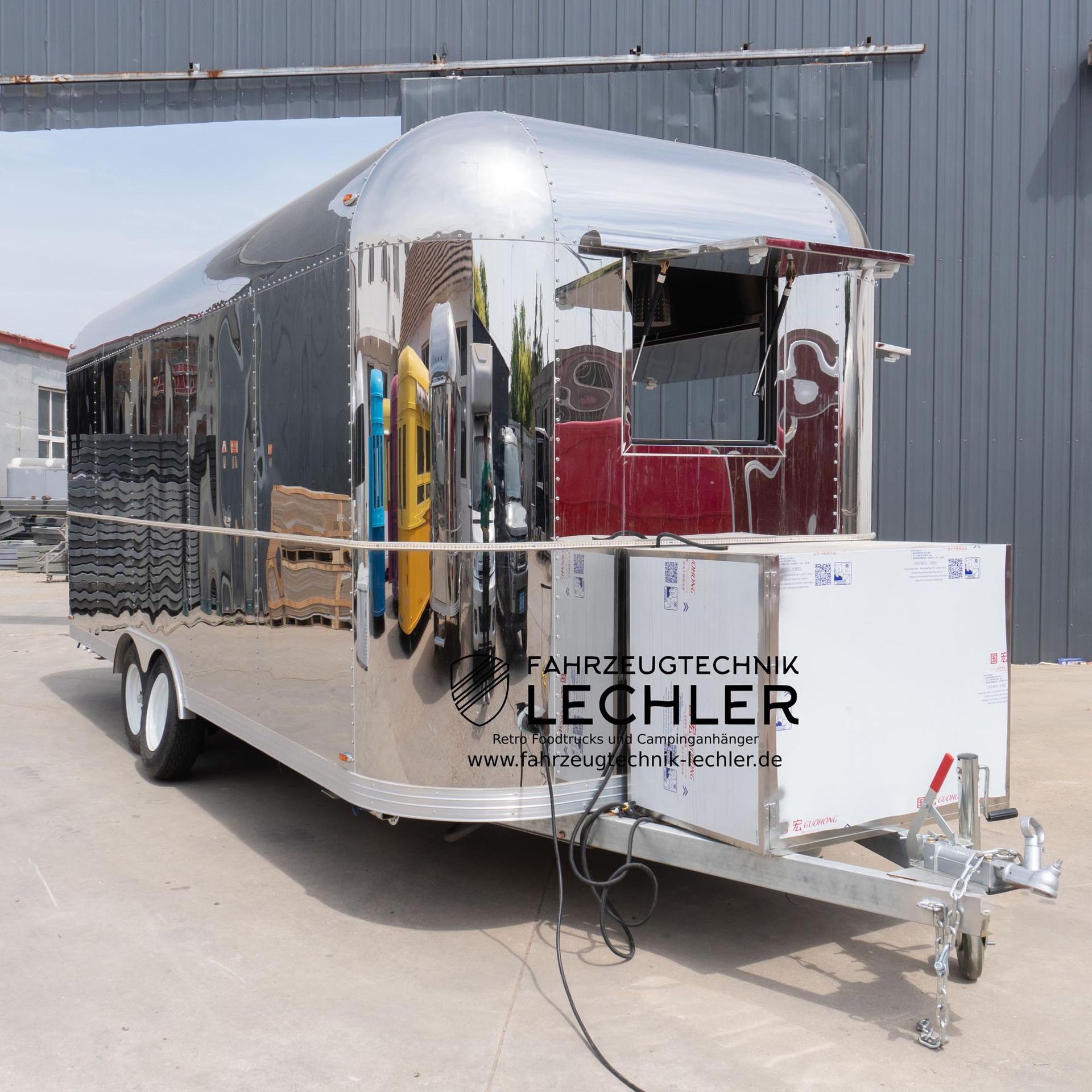 Glänzender silberner Imbisswagen mit großem Ausgabefenster, weißen Rädern und Anhängerkupplung.