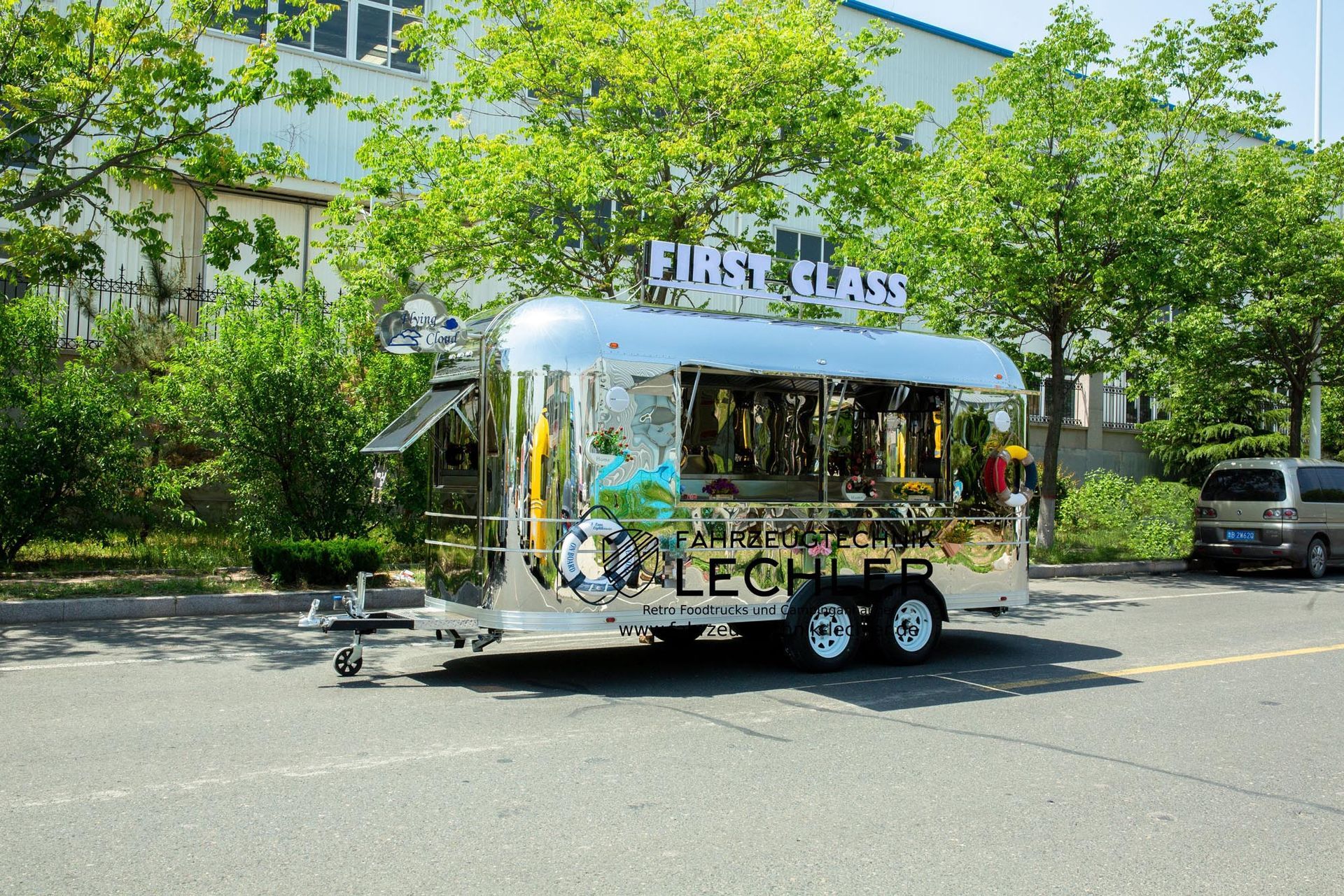 Ein glänzender Imbisswagen mit dem Schild „First Class“ parkt am Straßenrand.