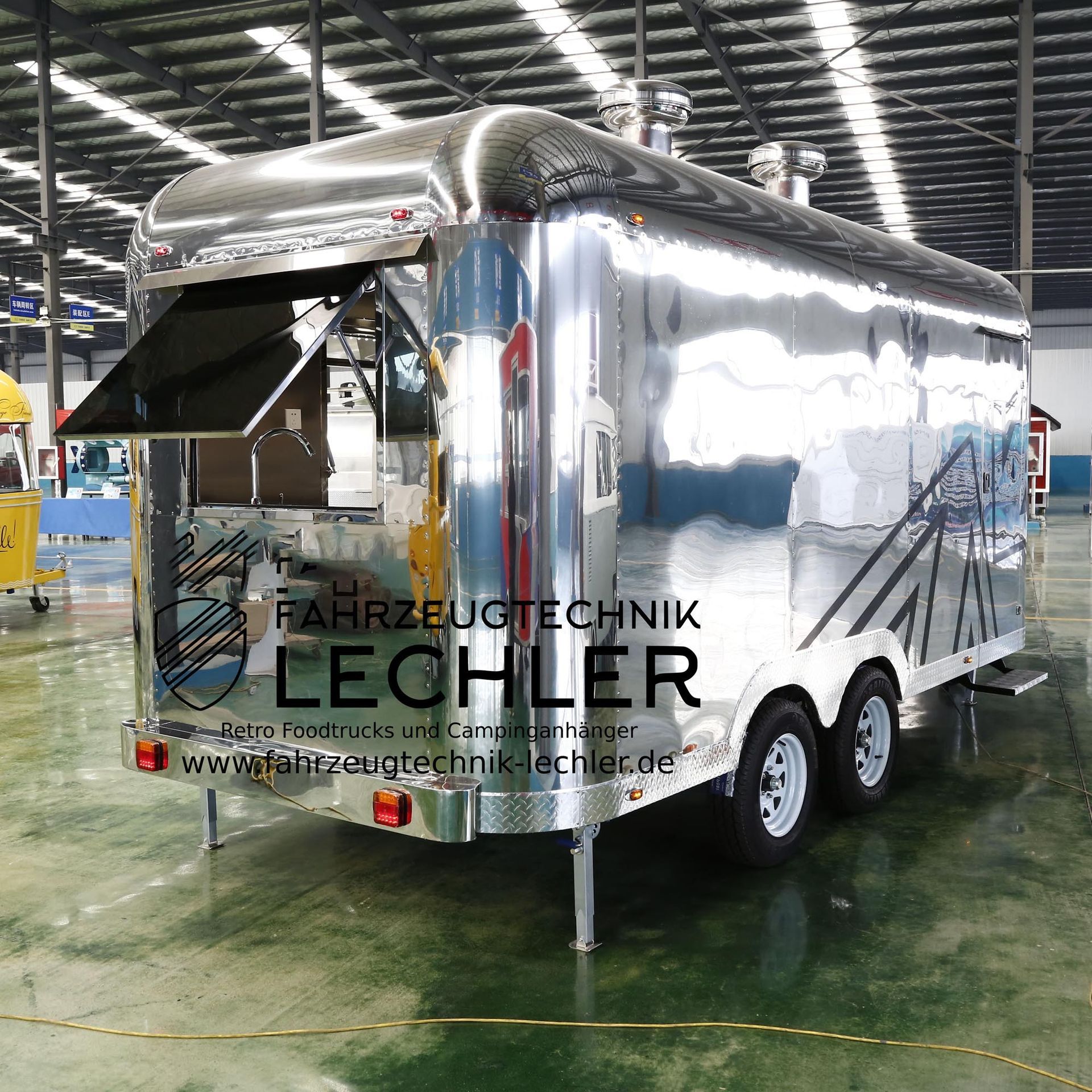 Ein glänzender, silberner Imbisswagen mit offenem Ausgabefenster steht in einer Lagerhalle.