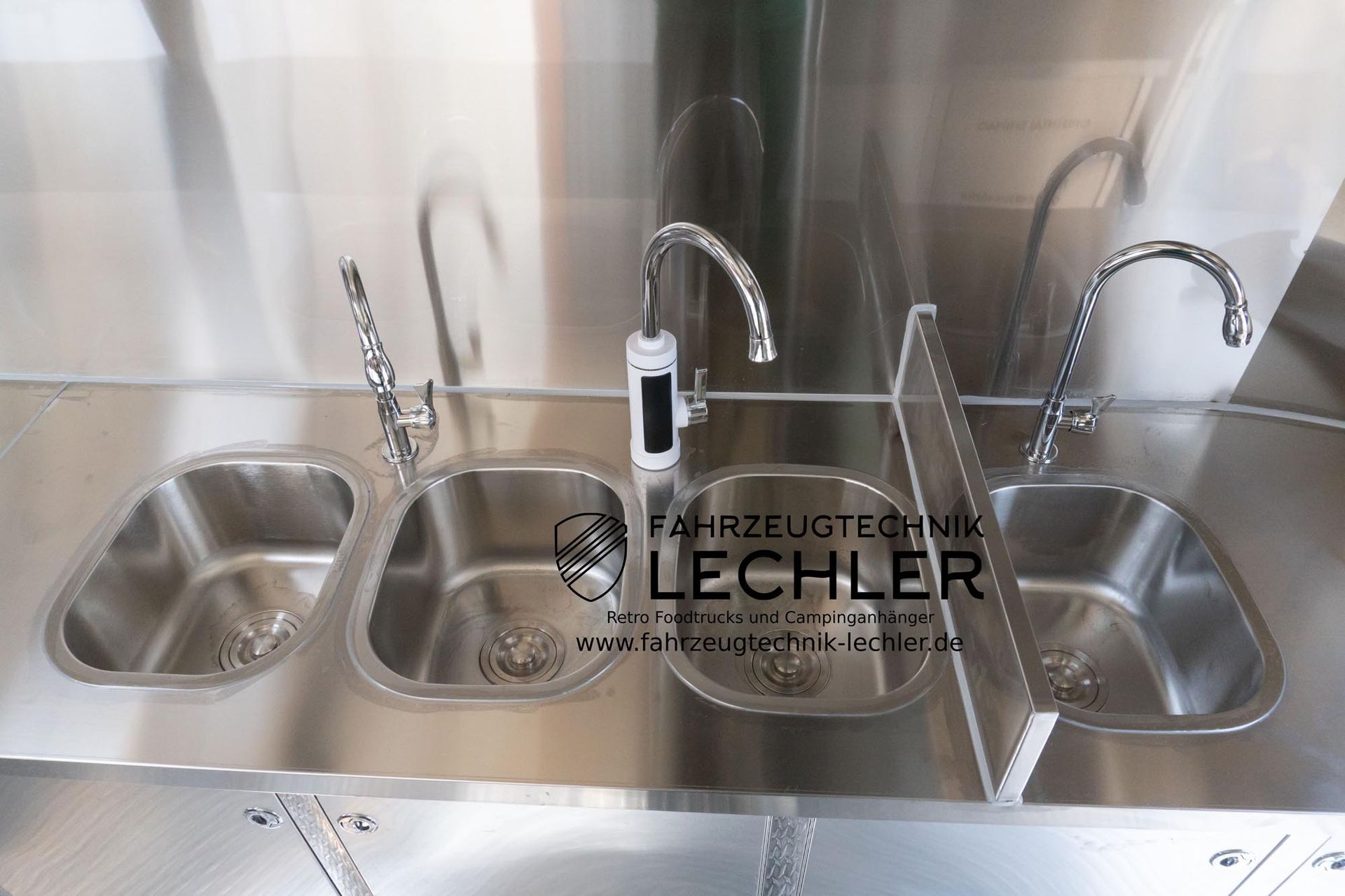 Edelstahlspülen mit drei Wasserhähnen in einem gewerblichen Umfeld.