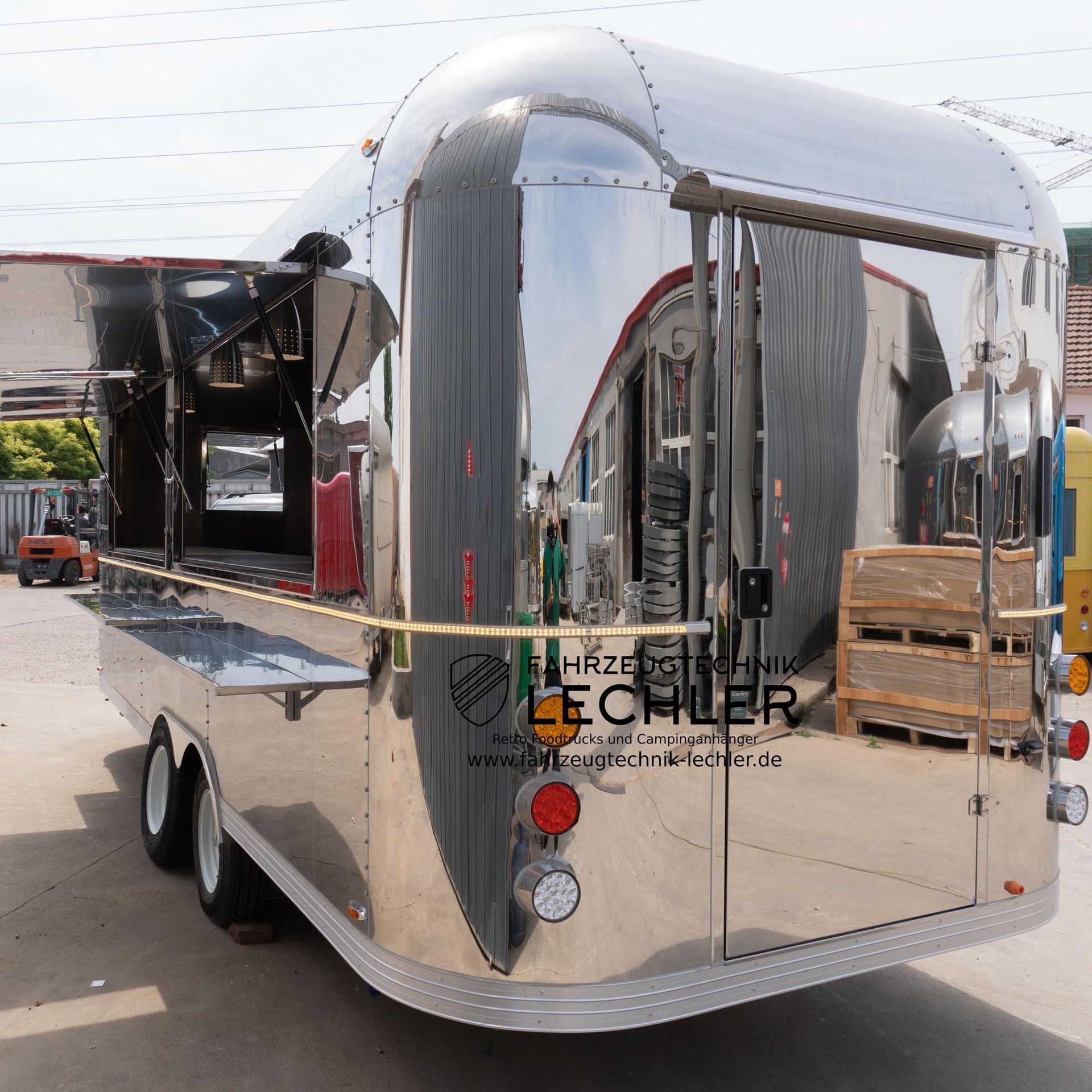 Ein glänzender, silberner Imbisswagen mit offenen Ausgabefenstern steht im Freien.