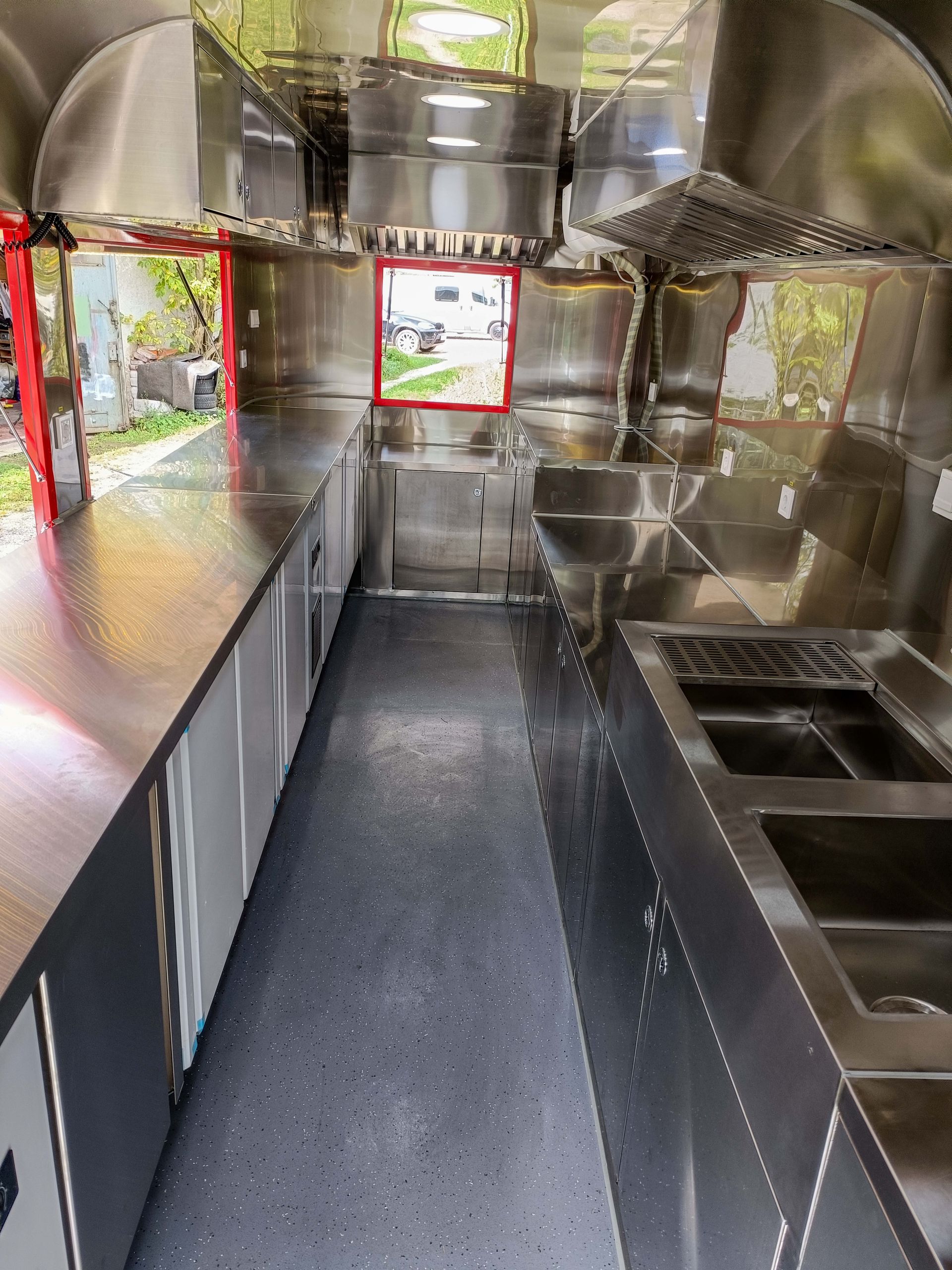 Im Inneren eines Imbisswagens: eine Kücheneinrichtung aus Edelstahl, lange Arbeitsflächen, Schränke und ein Fenster.