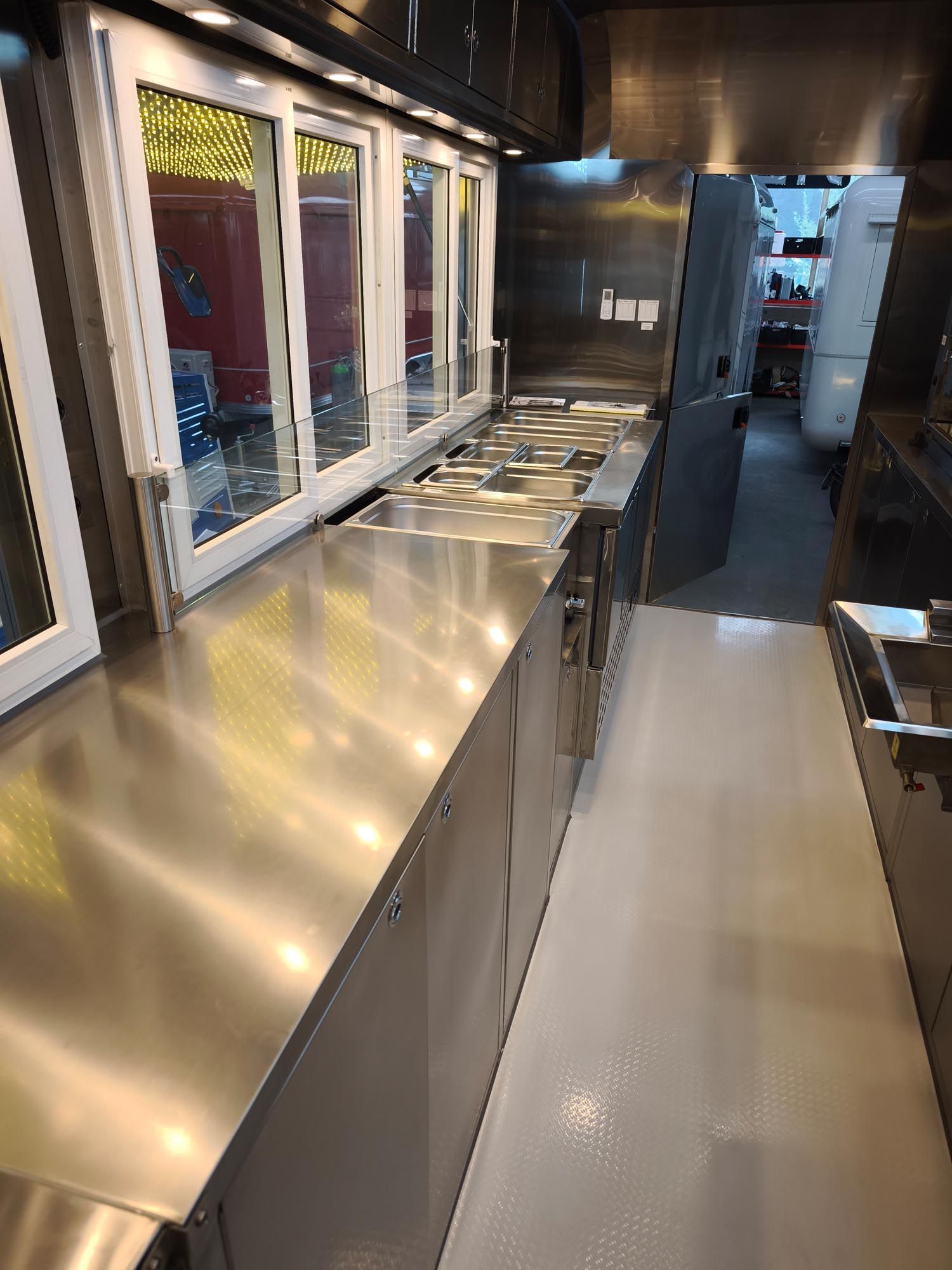 Edelstahlküche mit Kochflächen, Schränken und Fenstern.