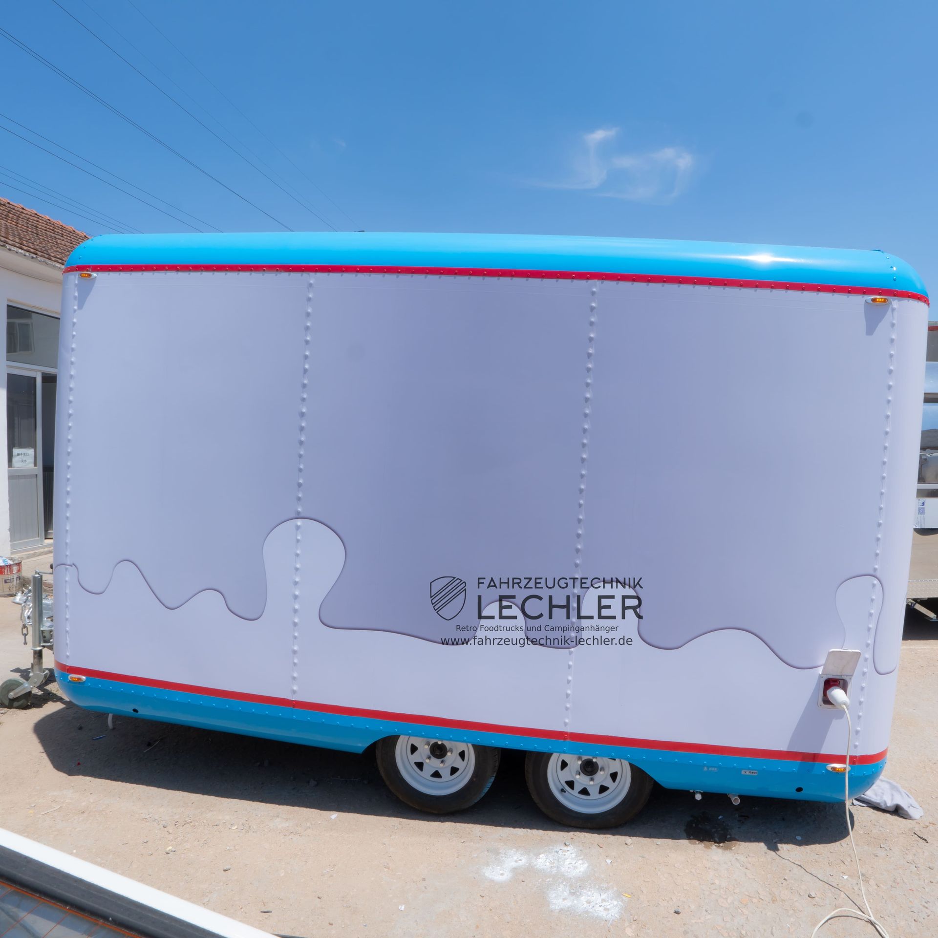 Weißer und blauer Imbisswagen mit dem „LECHLER“-Logo an einem sonnigen Tag.