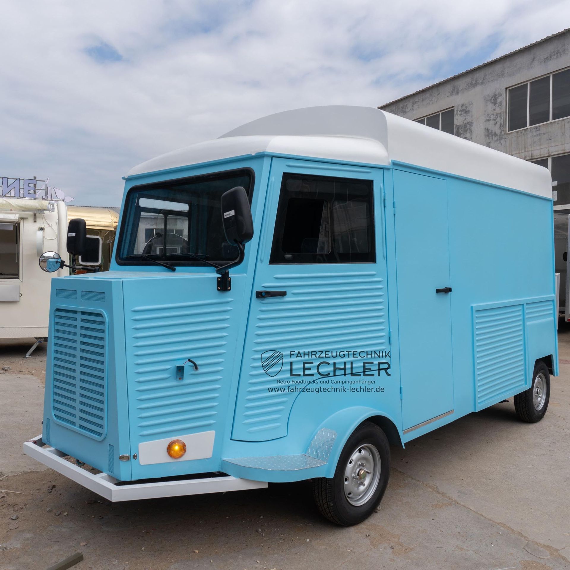 Hellblauer Imbisswagen mit weißem Dach, draußen geparkt.