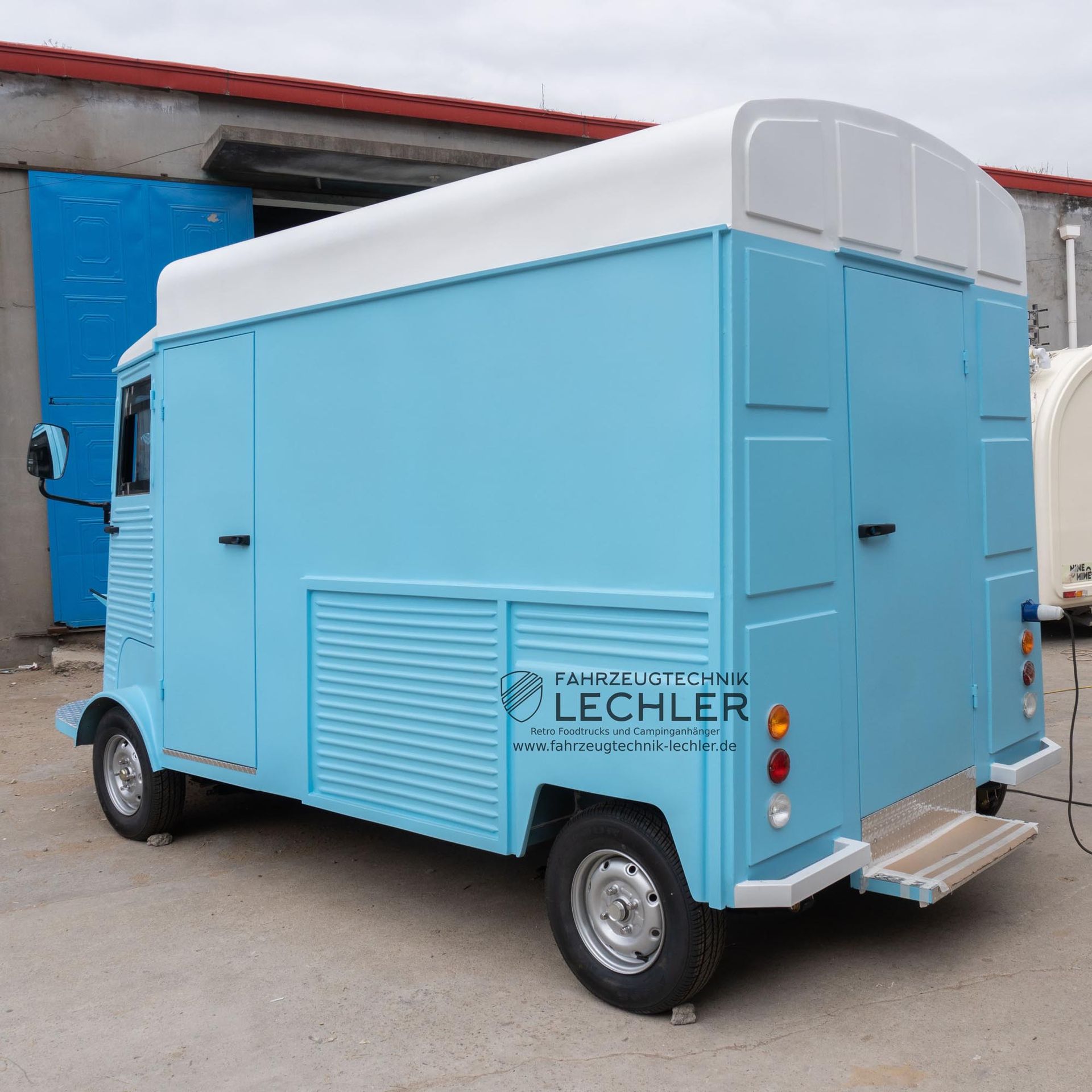 Hellblauer Imbisswagen mit weißem Dach, draußen geparkt.