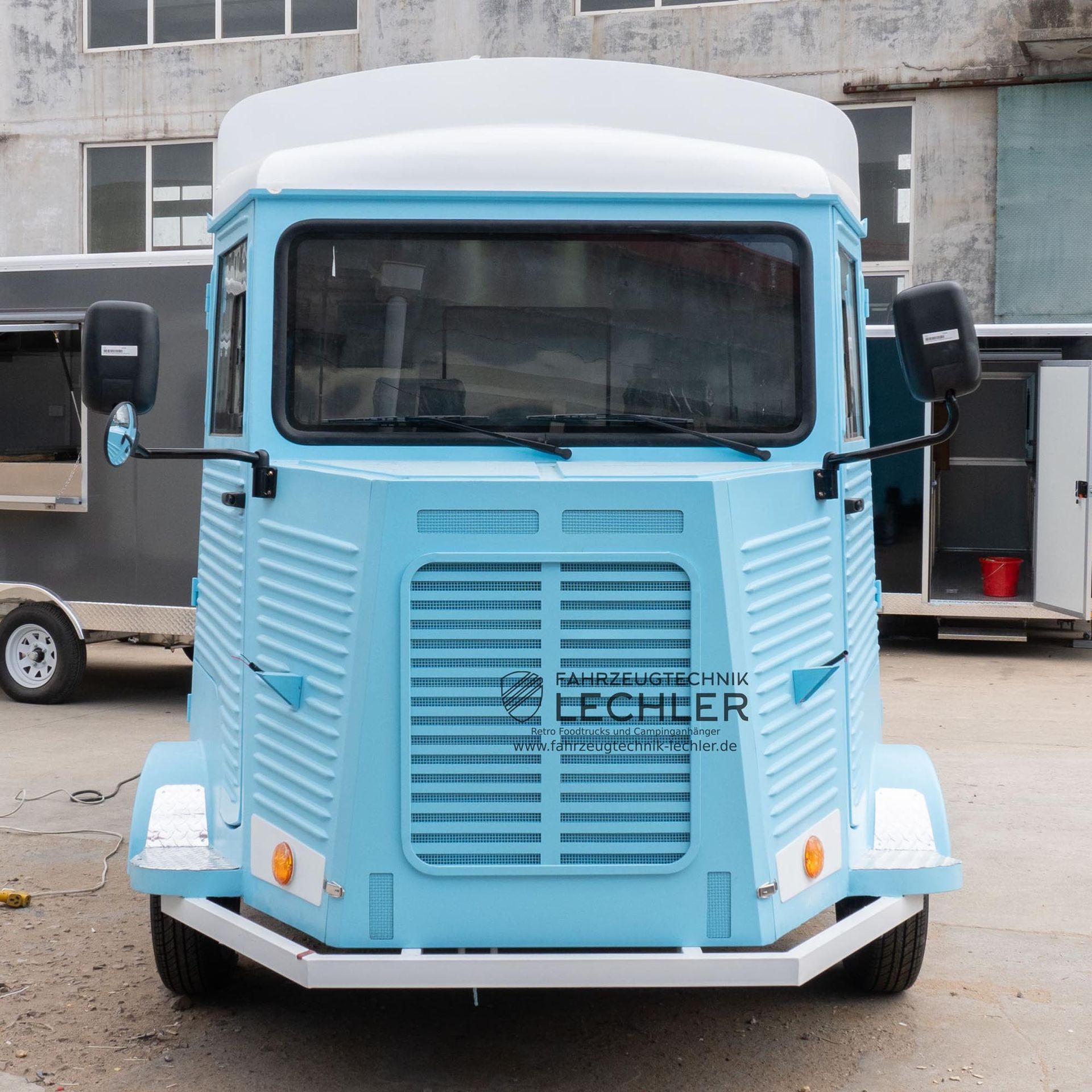 Ein blau-weißer Imbisswagen mit Lamellenfront steht draußen.