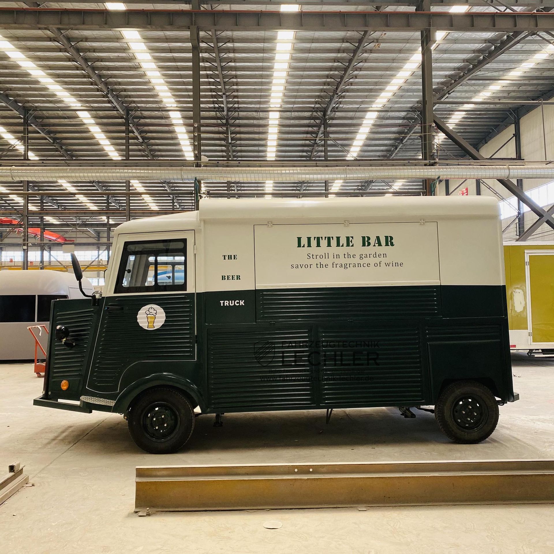 Grüner und weißer Imbisswagen mit der Aufschrift „Little Bar“ in einer Lagerhalle.