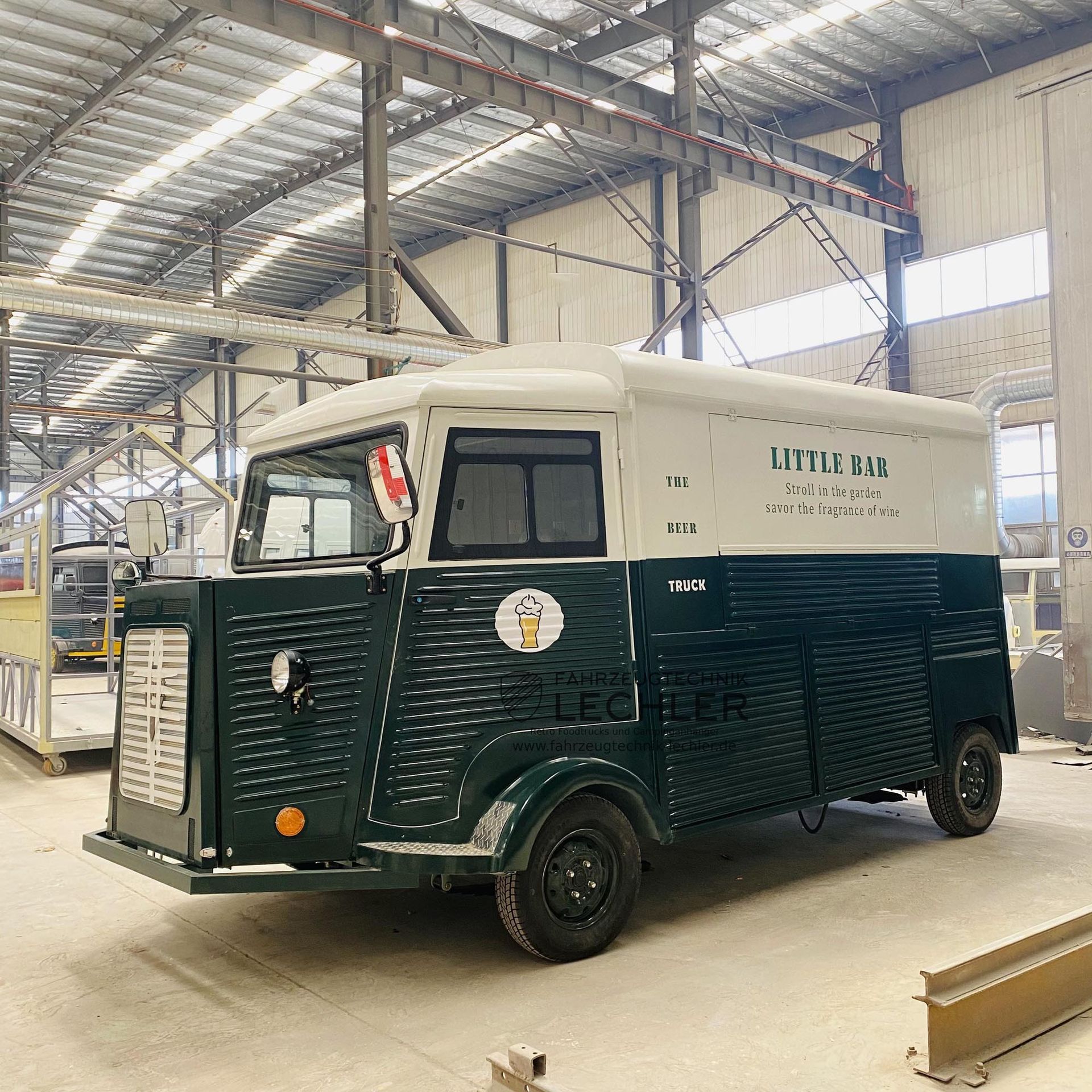 Ein grüner und weißer Imbisswagen in einer großen Lagerhalle. An der Seite ist der Schriftzug „LITTLE JOYS“ zu sehen.