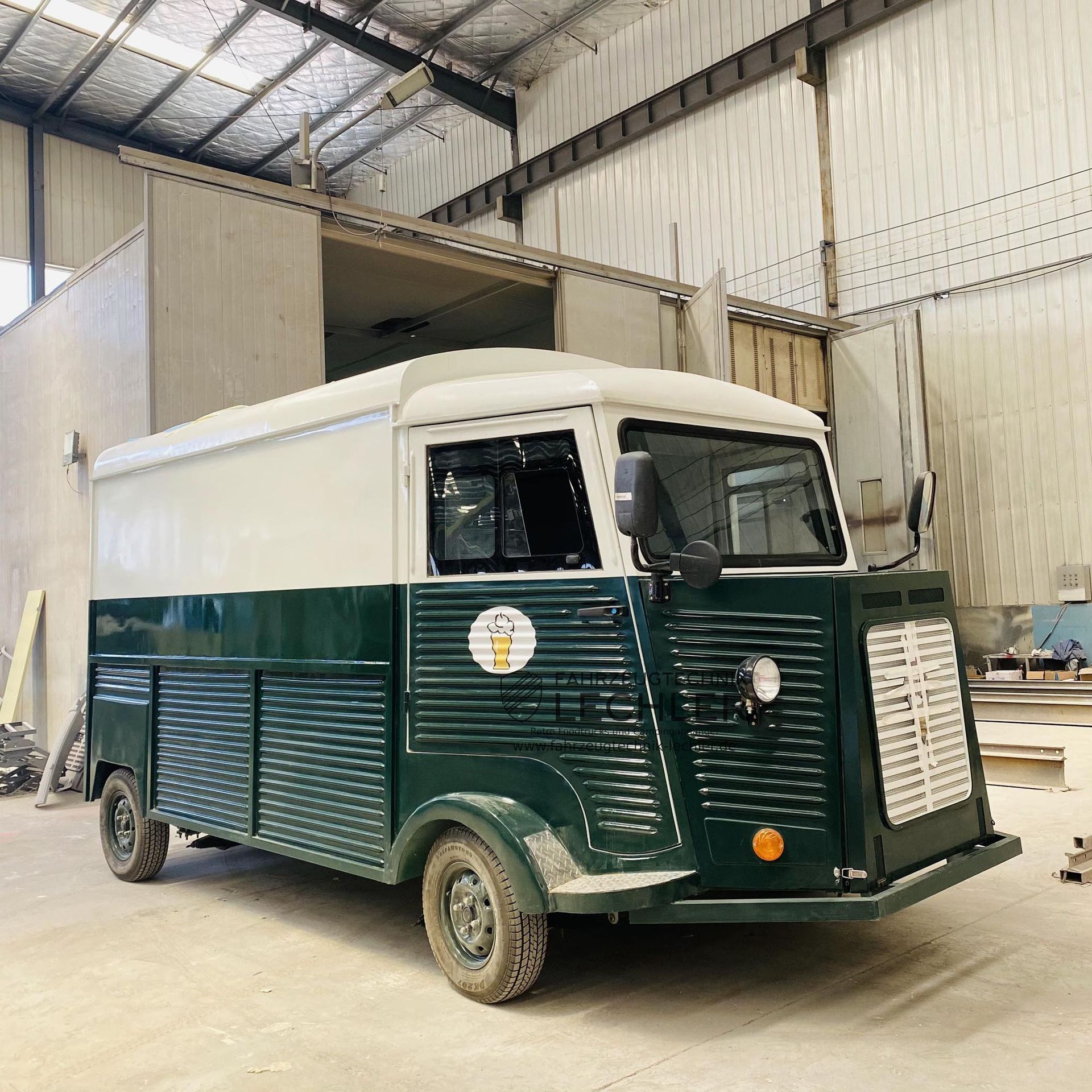 Ein grüner und weißer Imbisswagen parkt in einer Lagerhalle.