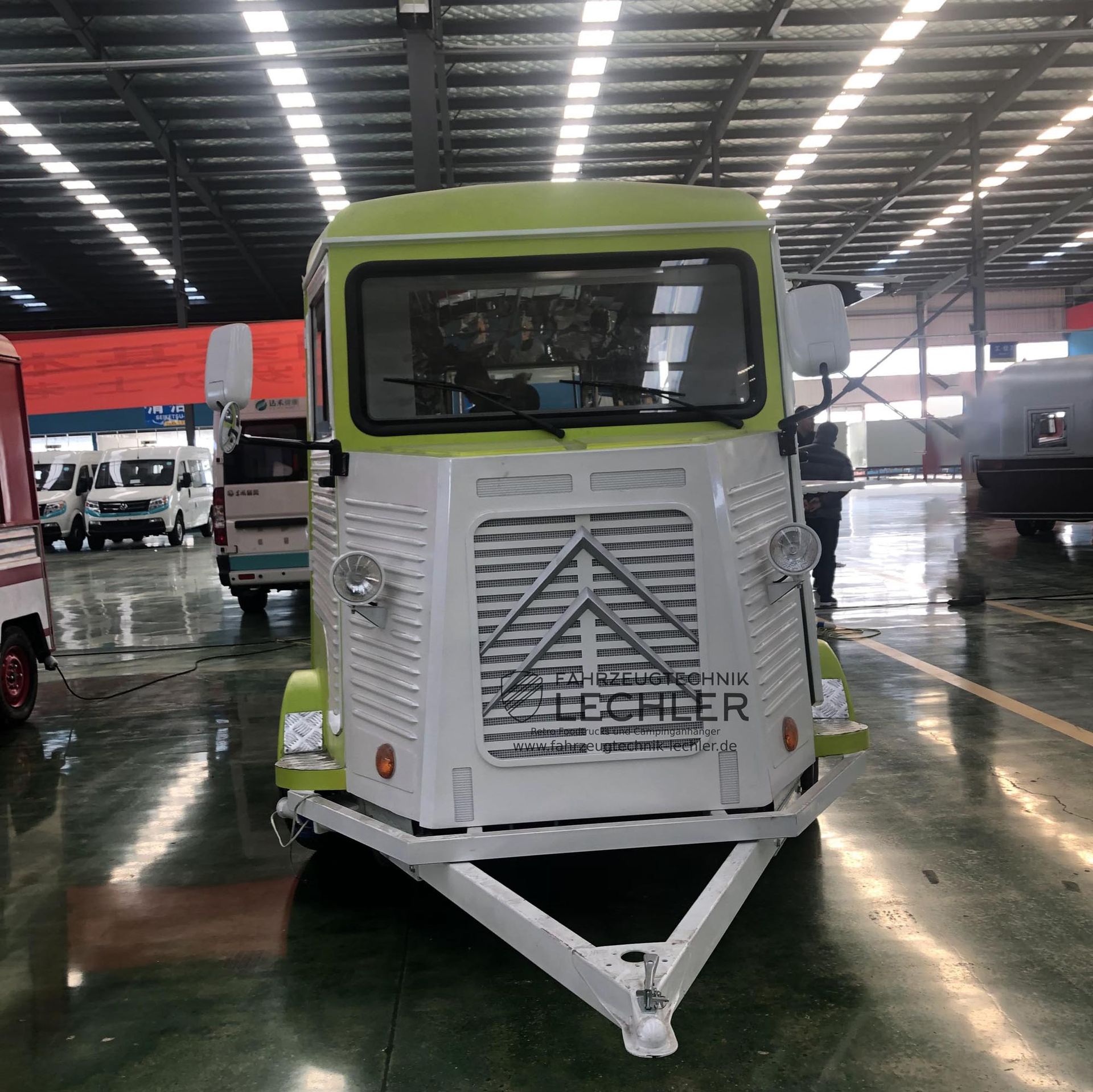 Ein hellgrüner und weißer Imbisswagen im Retro-Design, der in einem Gebäude geparkt ist.