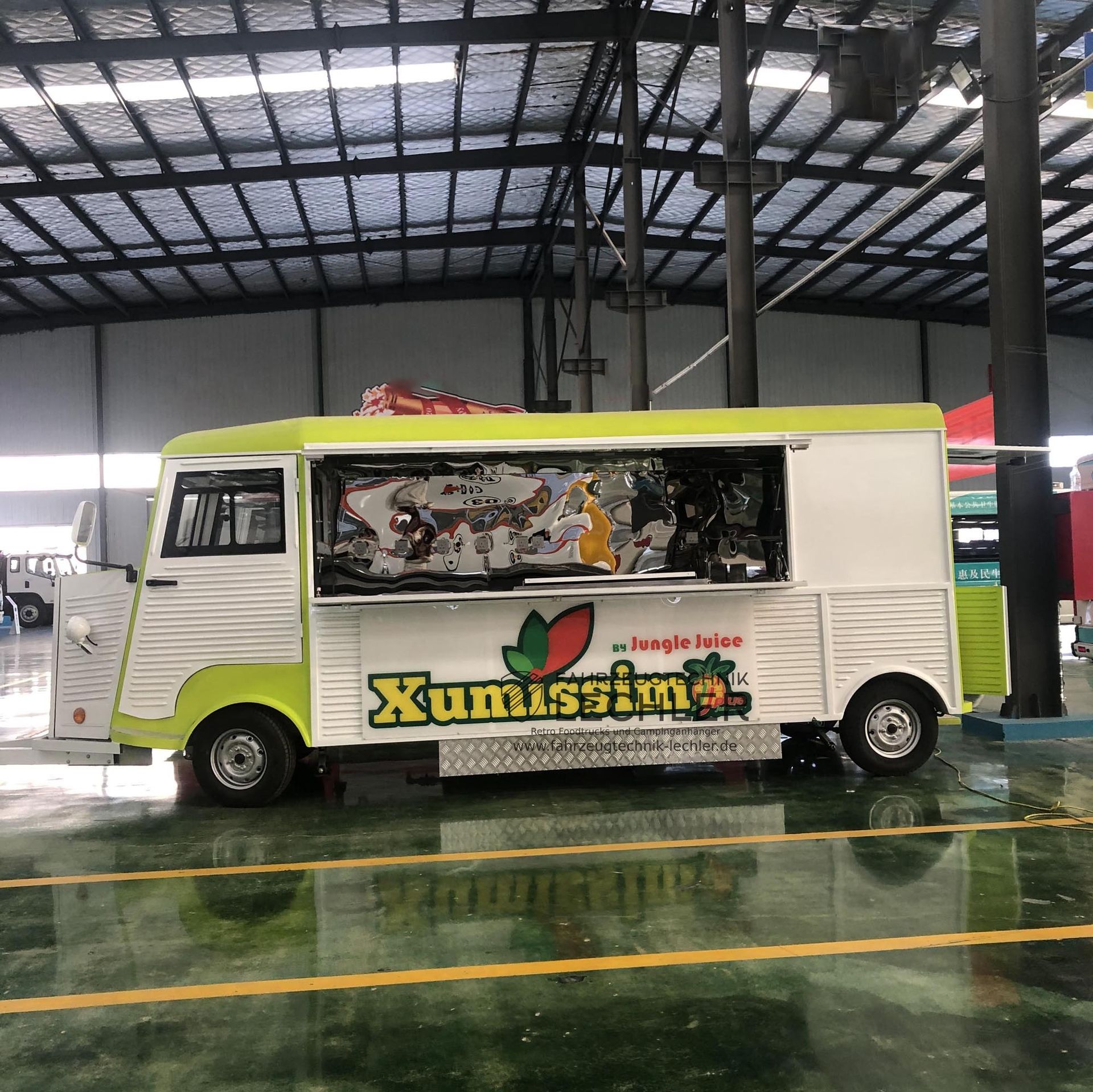 Ein Imbisswagen mit grün-weißer Außenfarbe, der in einem Gebäude geparkt ist.