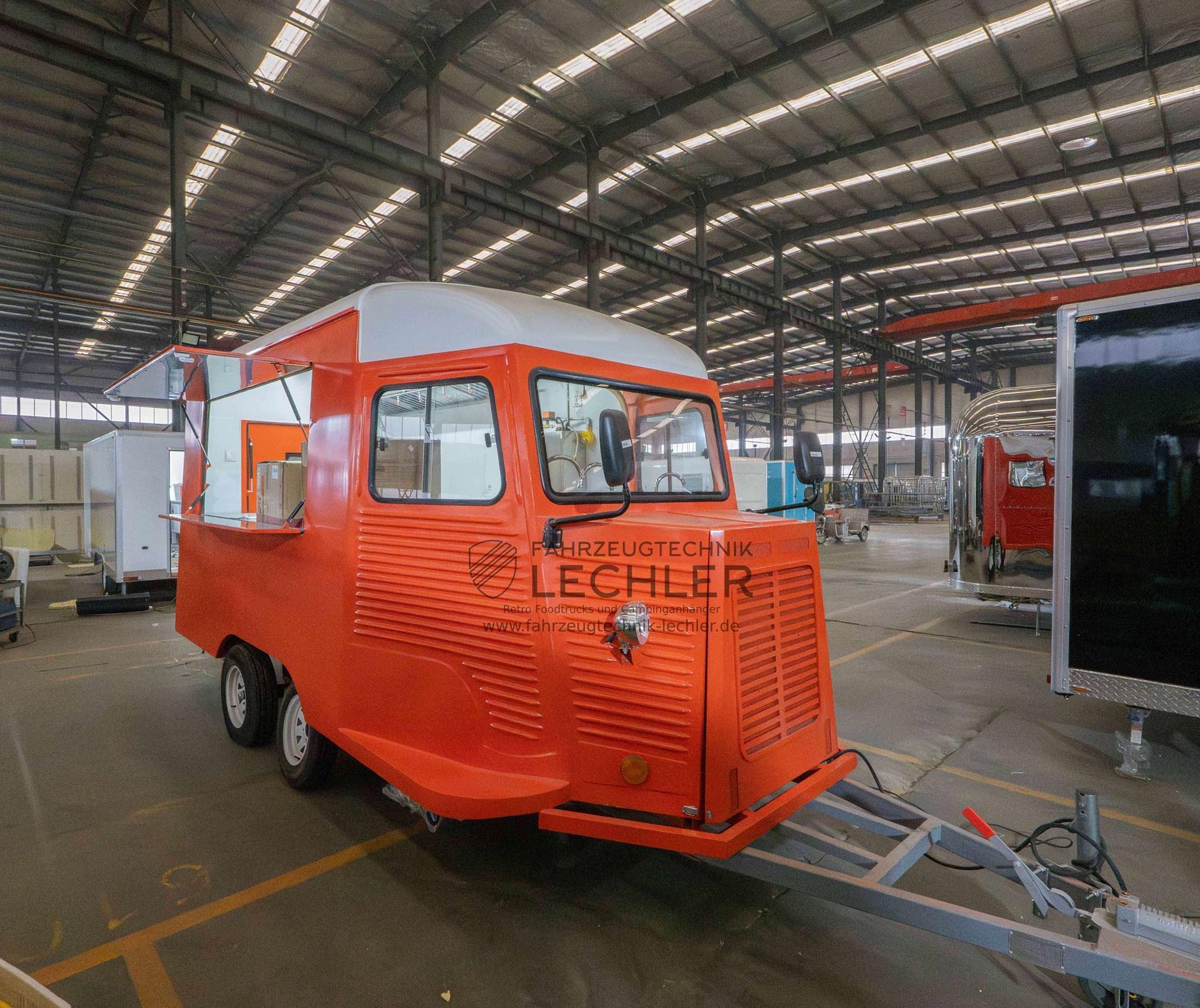 Oranger Imbisswagenanhänger in einem Fabrikgelände.