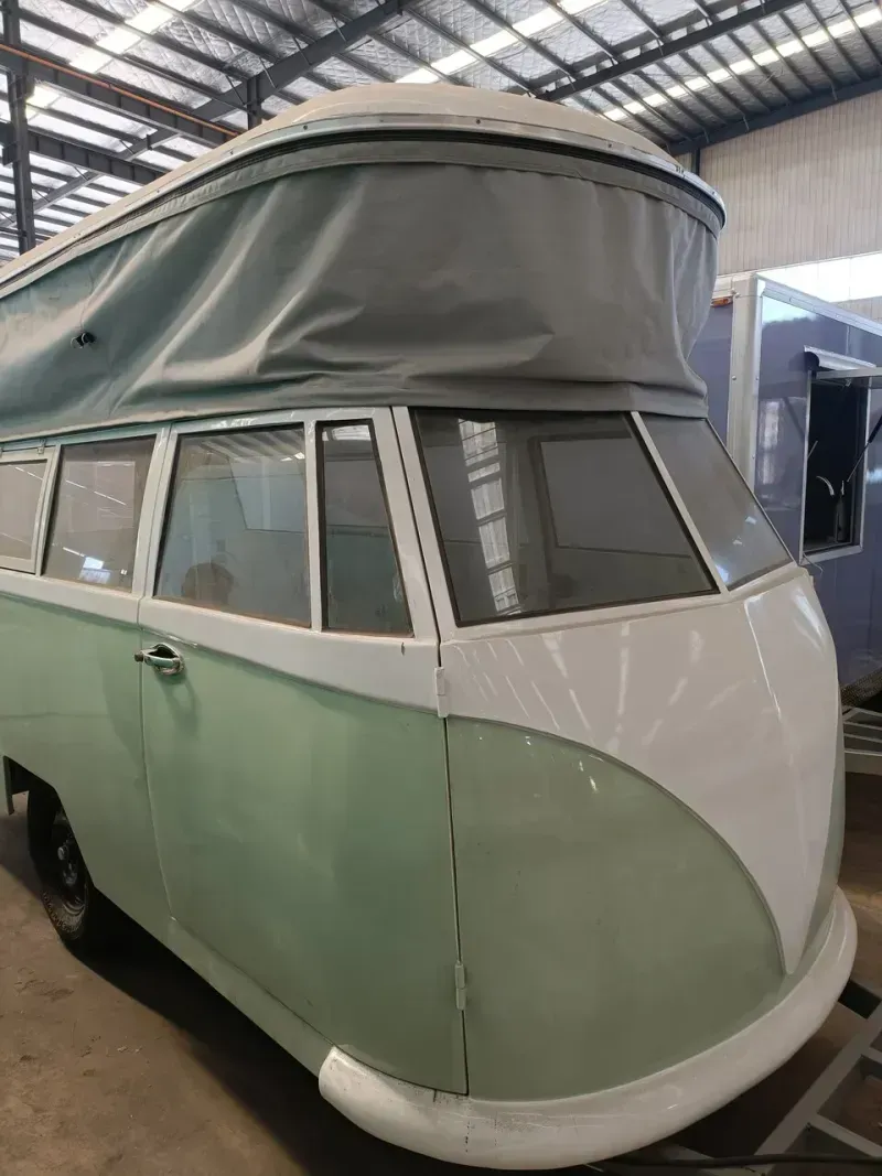 Grüner und weißer Oldtimer-Wohnwagen mit Aufstelldach.