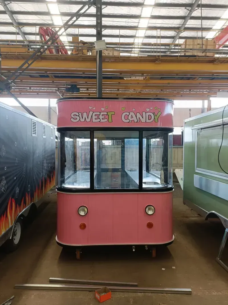 Ein rosafarbener Imbisswagen mit der Aufschrift „Sweet Candy“ und großen Fenstern steht in einer Lagerhalle.