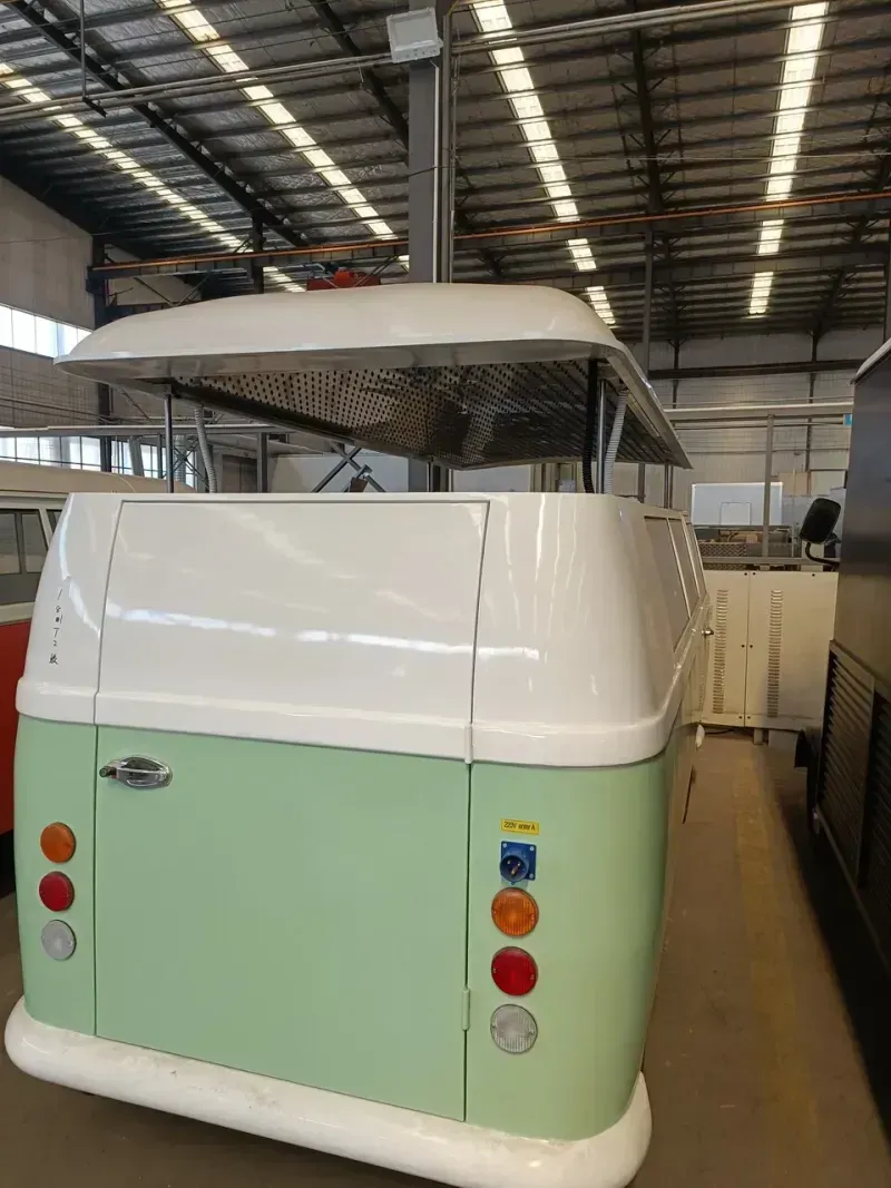 Grüner und weißer Retro-Imbisswagen mit Vordach, in einem Gebäude.