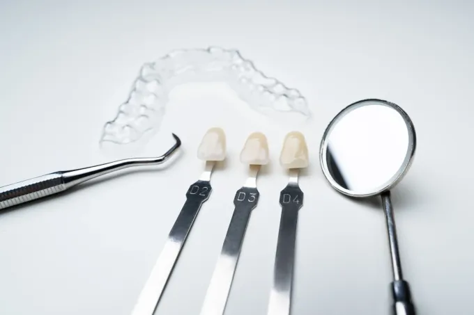 Instrumental dental: alineador transparente, guías de colores, espejo y sonda sobre una superficie blanca.