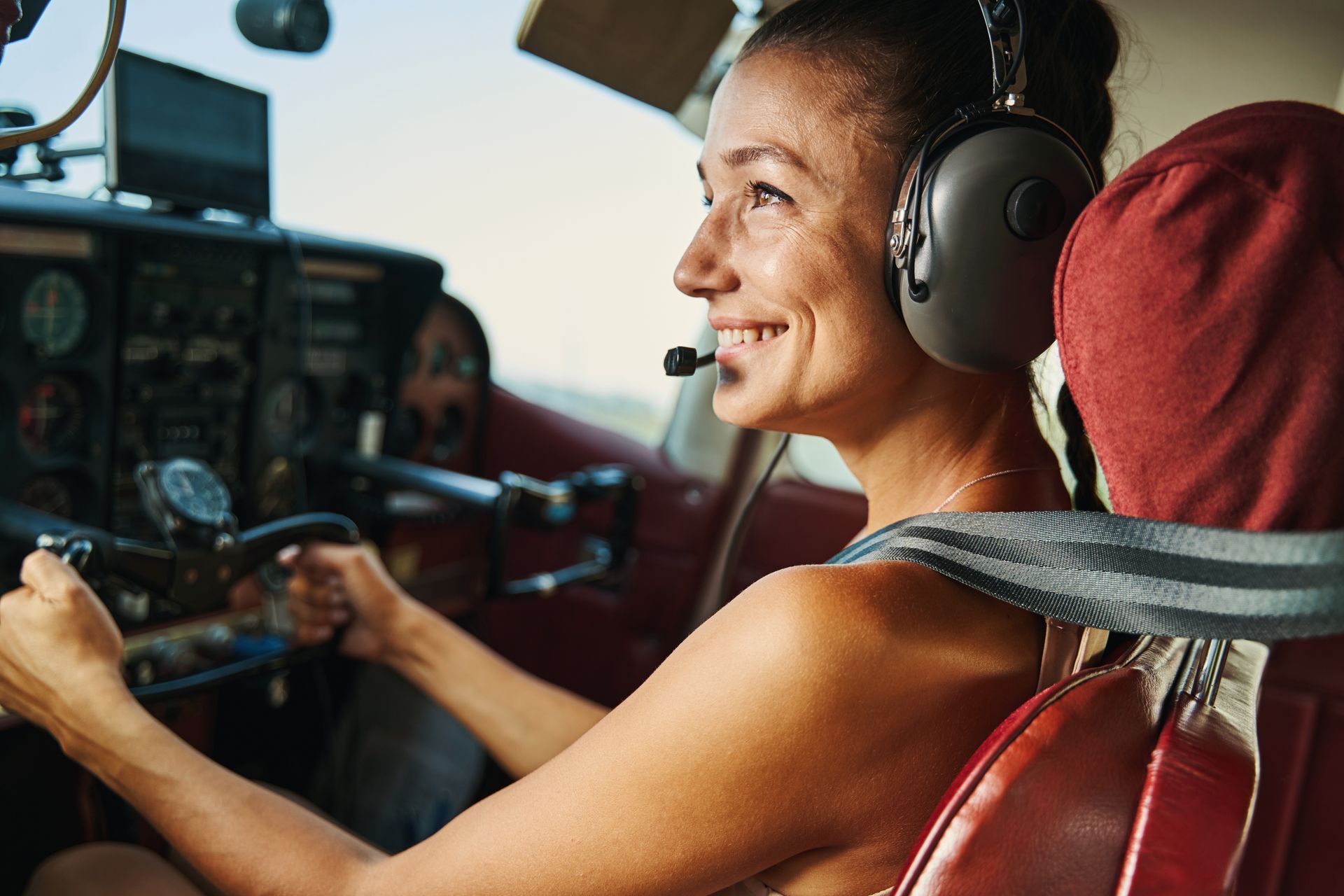 Pilote souriant aux commandes d’un avion, portant un casque de communication