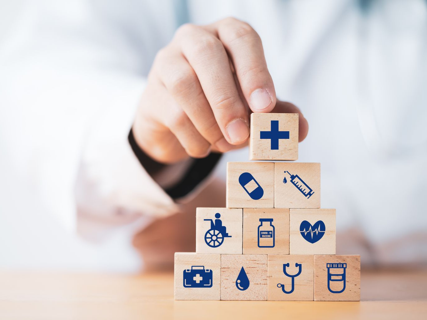 Mains tenant des cubes illustrés de symboles médicaux et de prévention santé