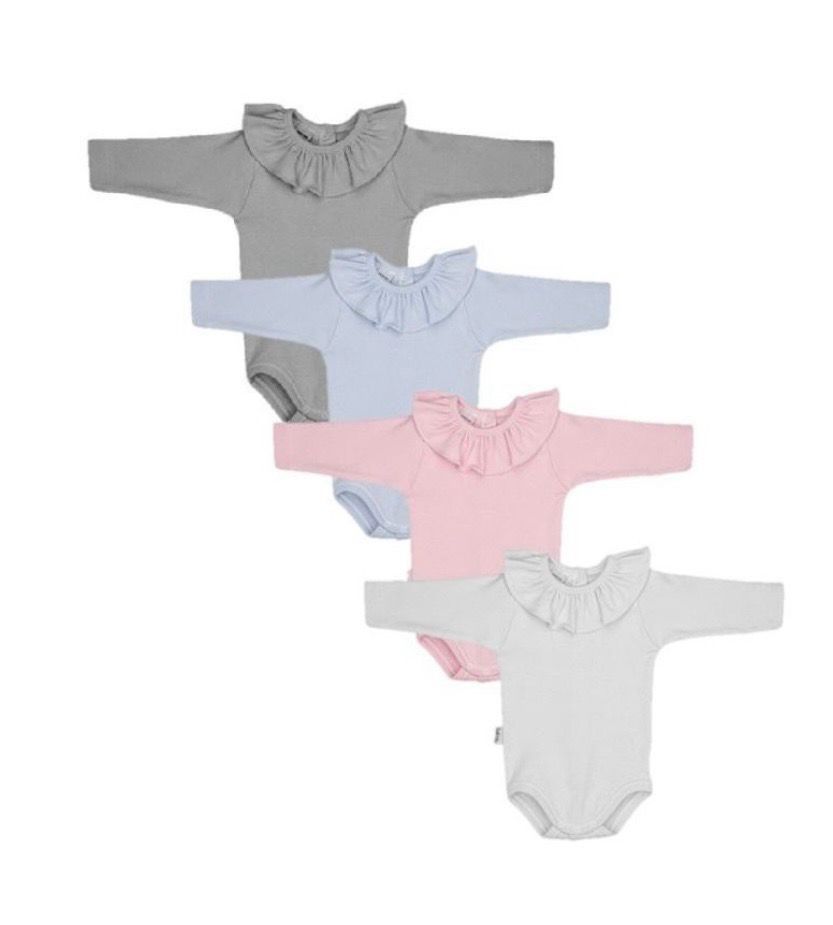 Cuatro monos para bebé en gris, azul, rosa y blanco, cada uno con cuello con volantes y mangas largas.