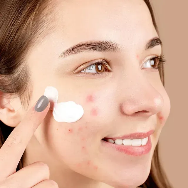 Una mujer se aplica crema en la cara.