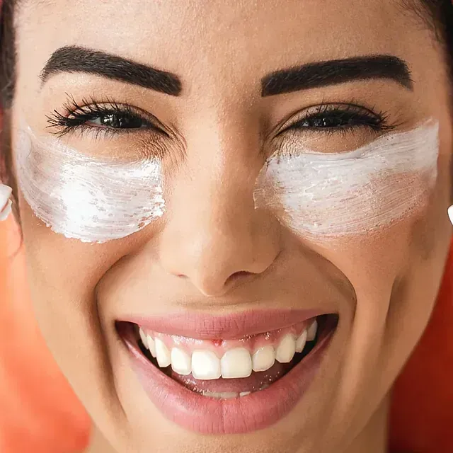 Un primer plano del rostro de una mujer con crema en los ojos.