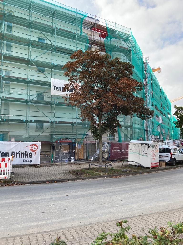 Gerüstbau Klein - Baugerüst mit grünem Sicherheitsnetz um ein mehrstöckiges Gebäude