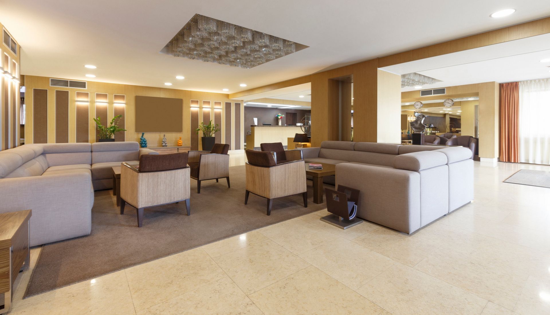 Salon moderne et spacieux avec des canapés beiges, des fauteuils et un éclairage chaleureux dans un intérieur ouvert.