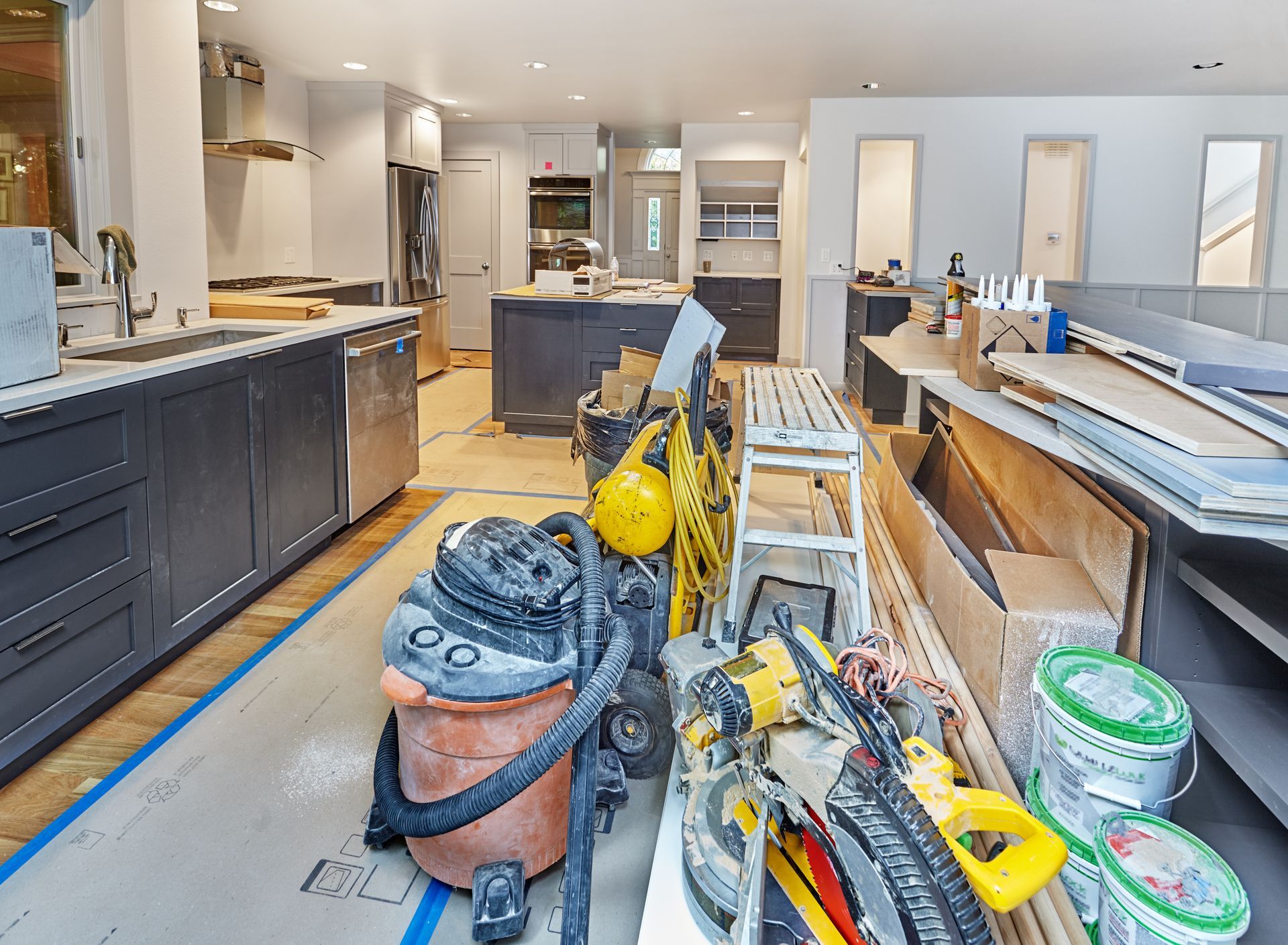 Rénovation de la cuisine en cours : outils et matériaux éparpillés sur le sol et les plans de travail.