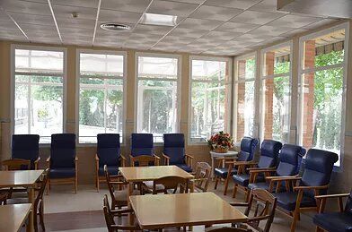 Una sala grande con mesas y sillas y muchas ventanas.