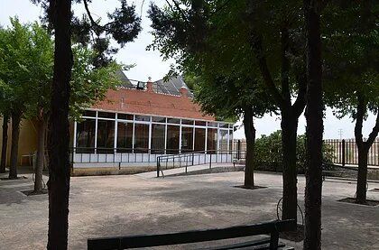 Un parque con árboles y un banco frente a un edificio.