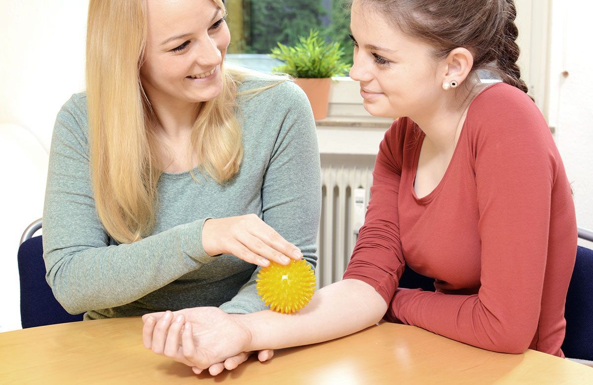 Zwei Frauen spielen mit einem gelben Ball an ihren Handgelenken