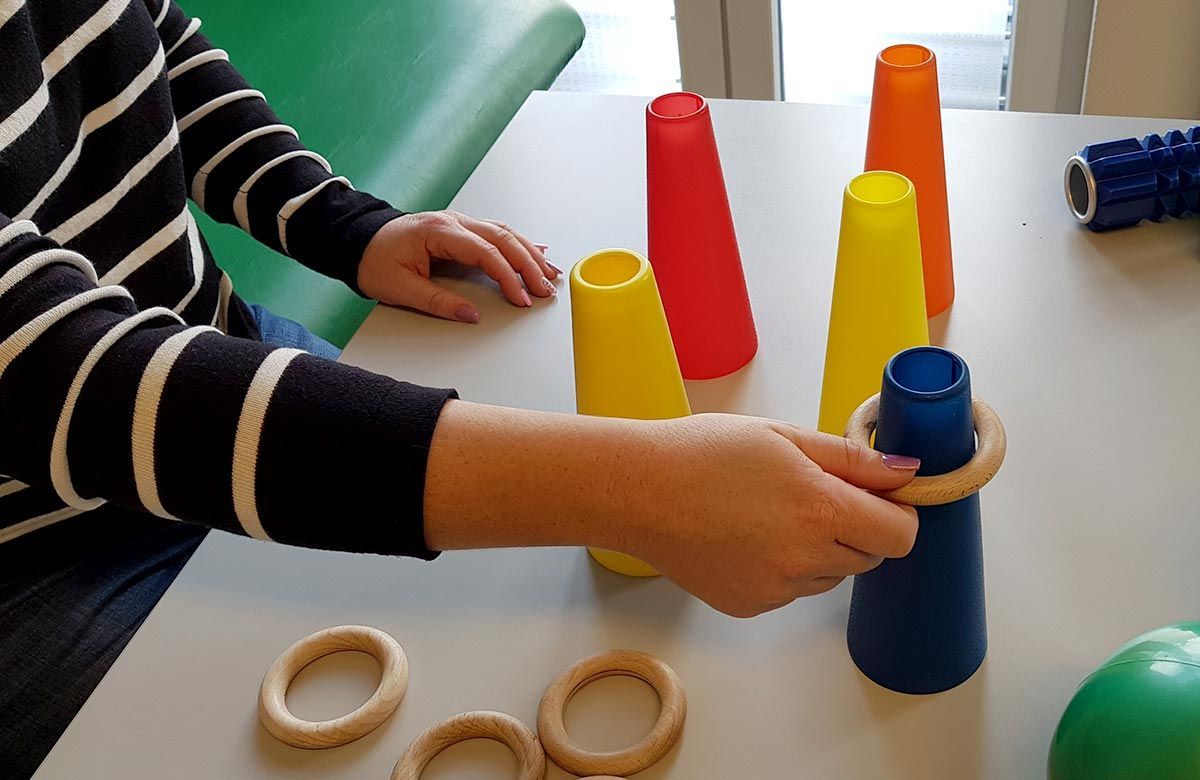 Eine Person spielt ein Spiel mit Bechern und Ringen