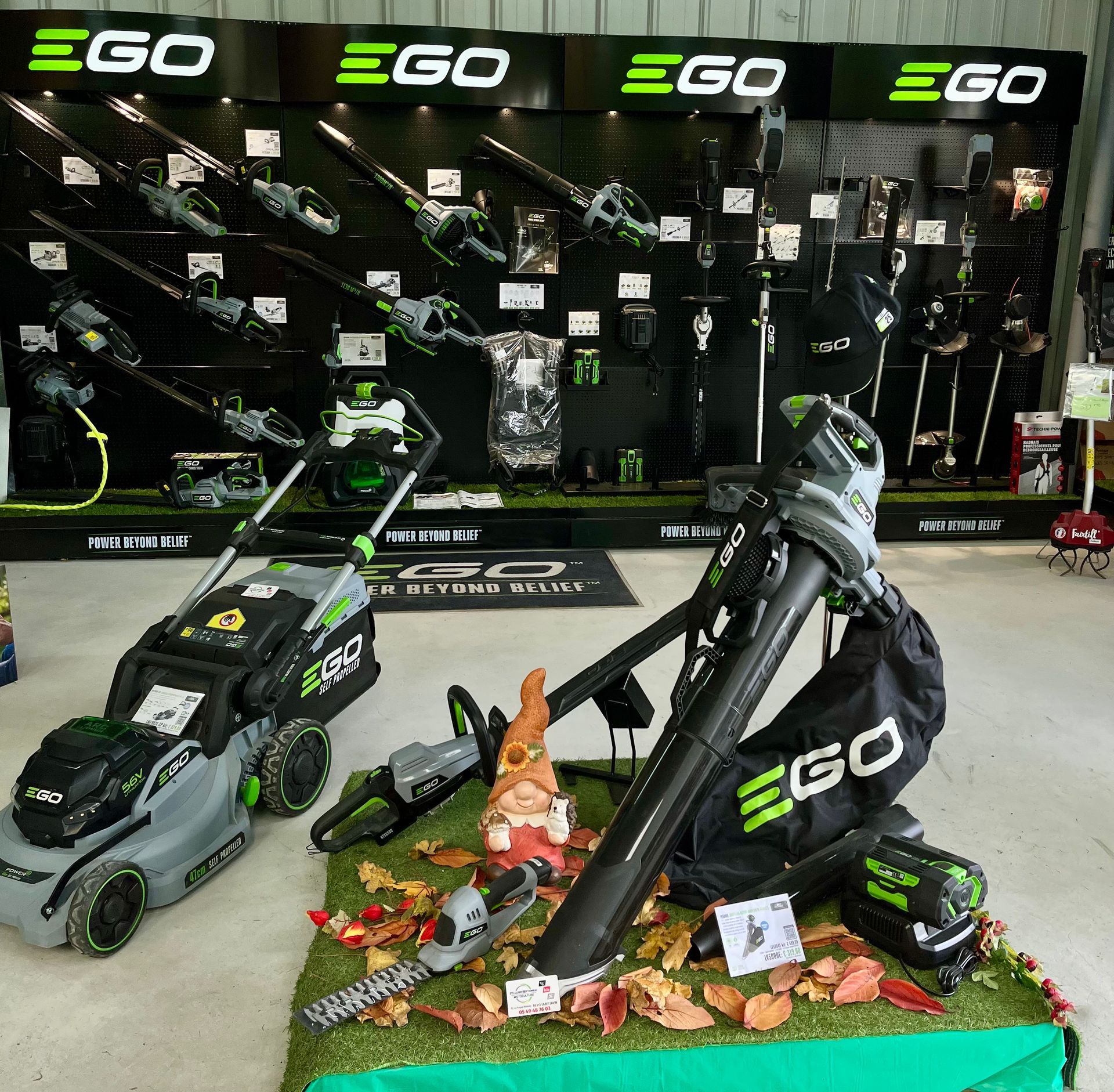 Présentation par EGO d'équipements de jardinage écologiques, notamment des tondeuses et des débroussailleuses, disposés dans une salle d'exposition.
