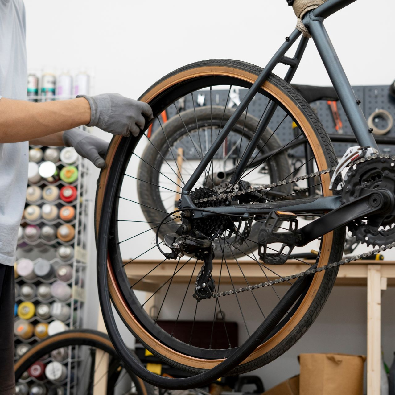 Gros plan sur un VTT noir en cours de nettoyage, une main gantée frottant la roue arrière.