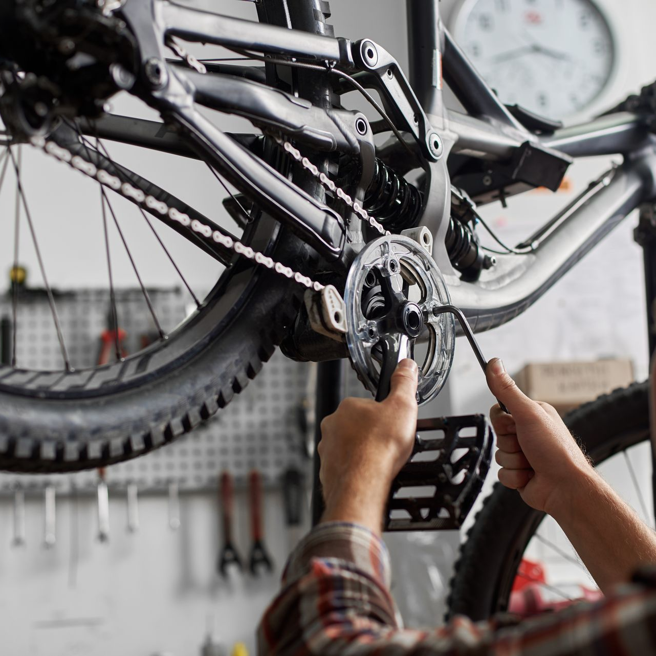Des mains réparent la chaîne et le dérailleur d'un VTT dans un atelier.