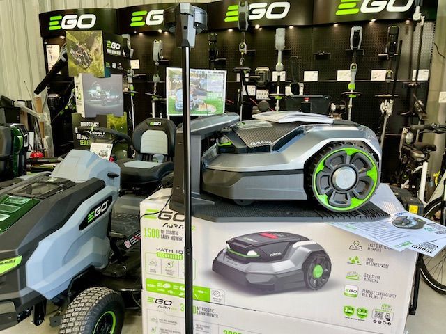 Présentoir d'outils de jardin EGO avec une tondeuse autoportée grise et sa boîte sur un stand en magasin.