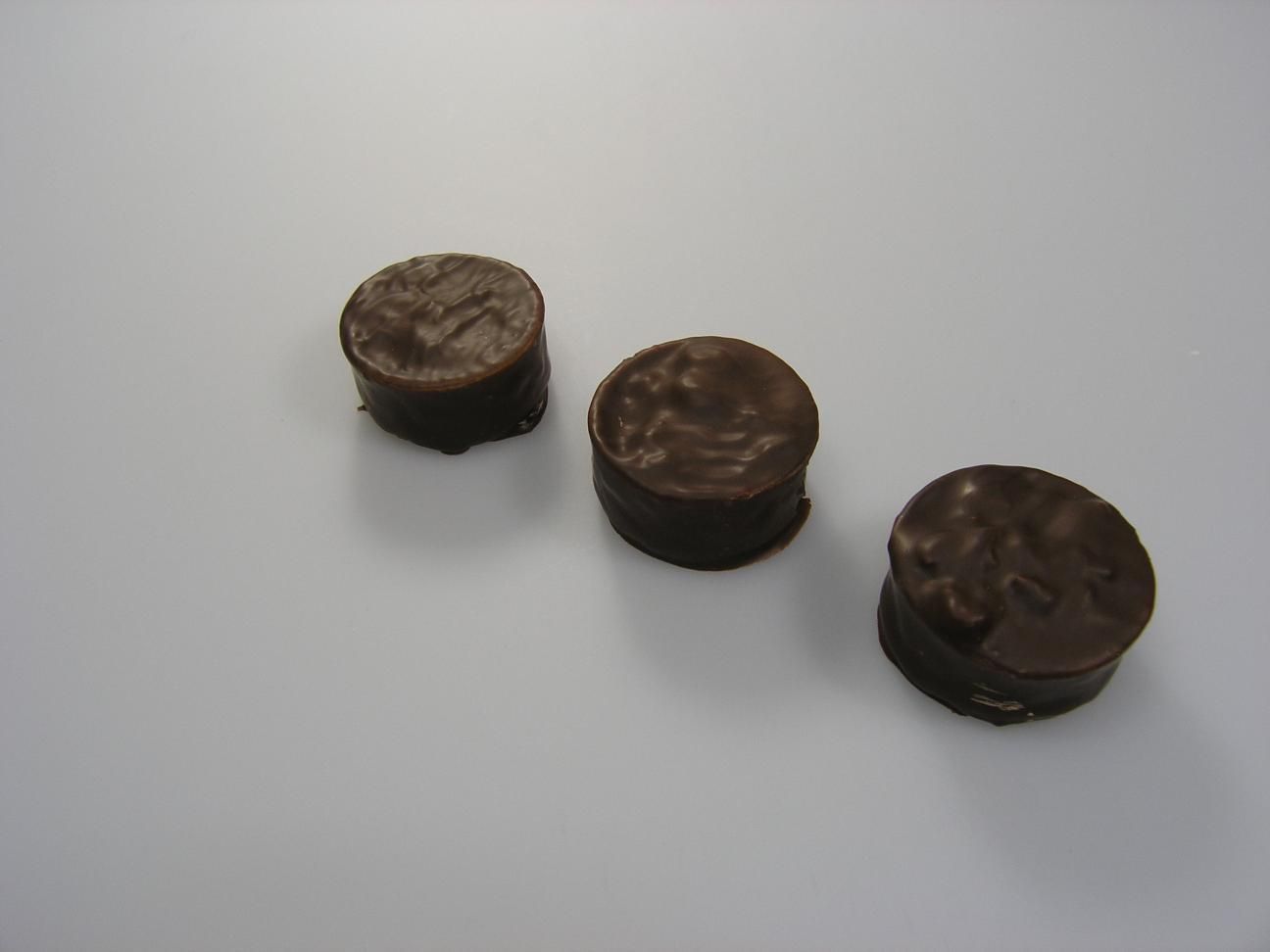 Trois pièces en chocolat sont alignées sur une surface blanche