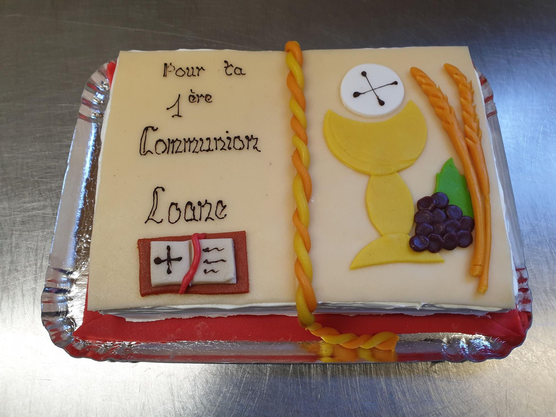 Un gâteau qui ressemble à un livre avec des symboles de communion dessus