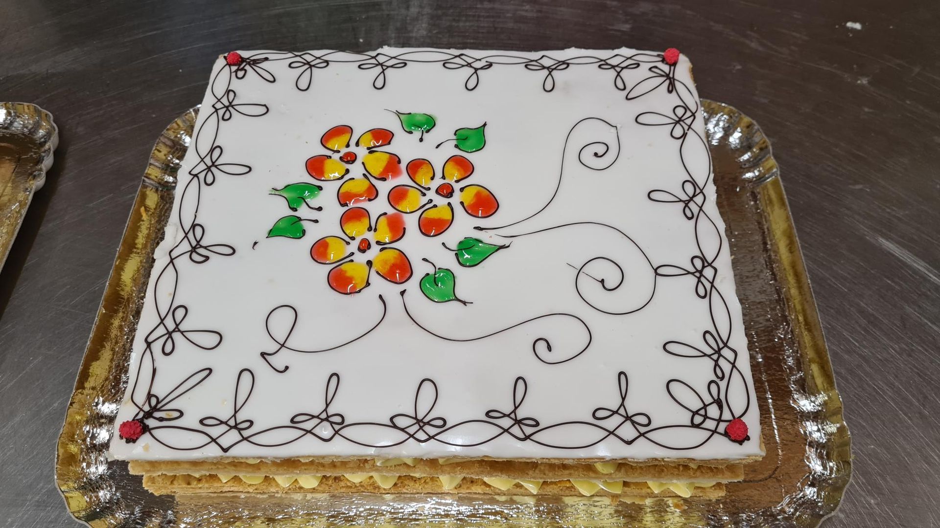 Un gâteau carré avec des fleurs et des tourbillons dessus