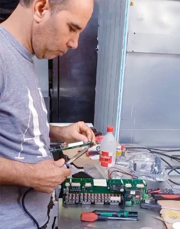 Un hombre con una camisa gris está trabajando en una placa base.