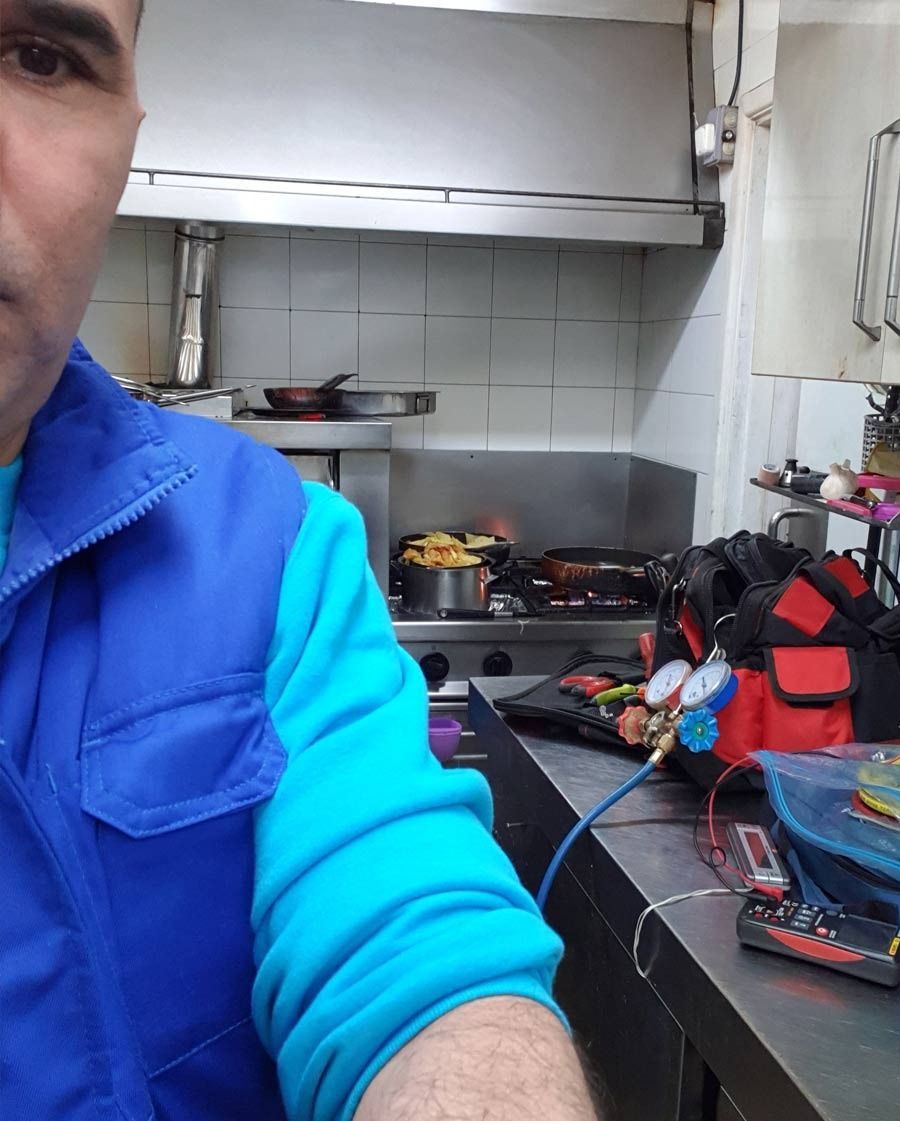 Un hombre con un chaleco azul está trabajando en una cocina.
