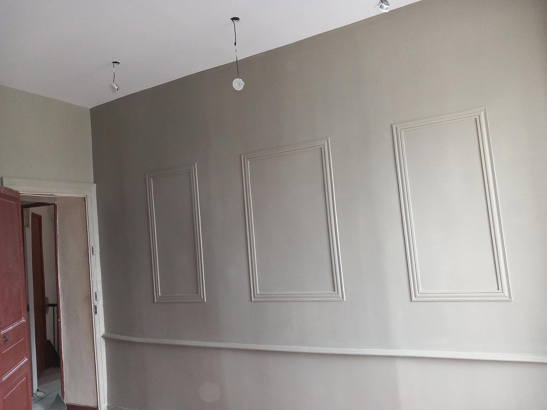 Une pièce en cours de rénovation avec un mur d'accent gris avec trois panneaux rectangulaires.